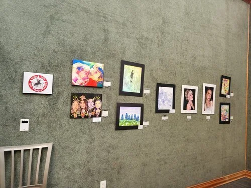 Colorful student paintings arranged across a gallery wall