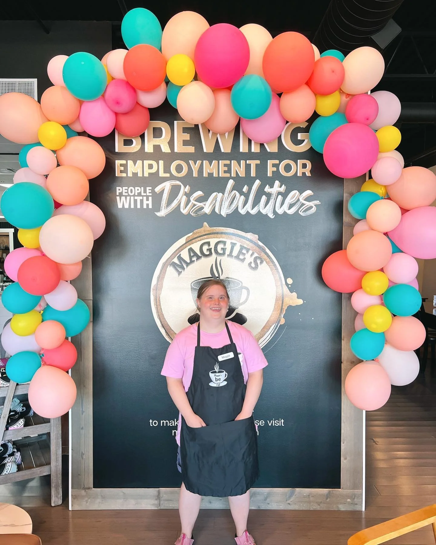 Maggie at the grand opening of Maggie's Place with a balloon banner