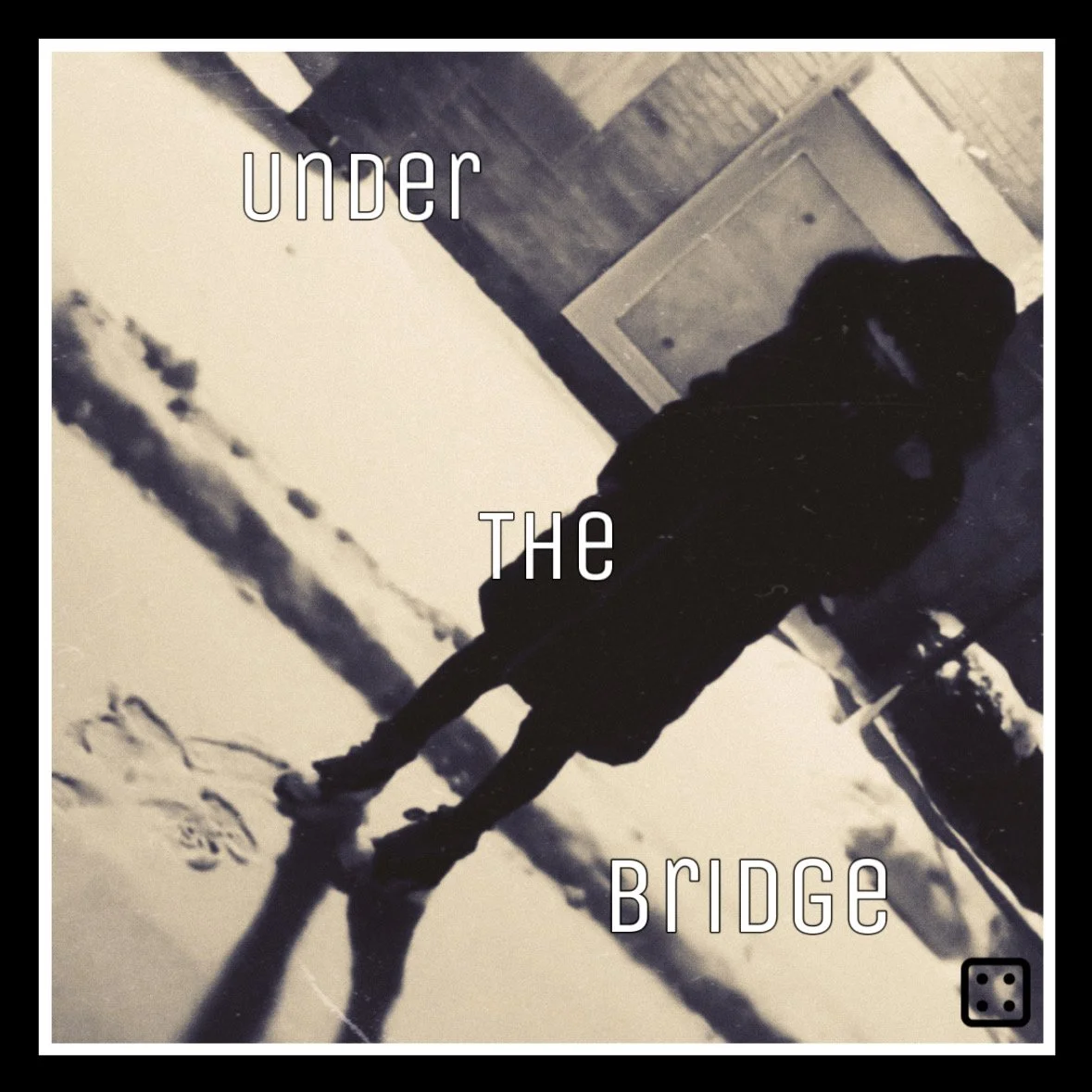 A person standing outside on snow-covered ground with their reflection visible in a puddle, with the words "under the bridge" superimposed.