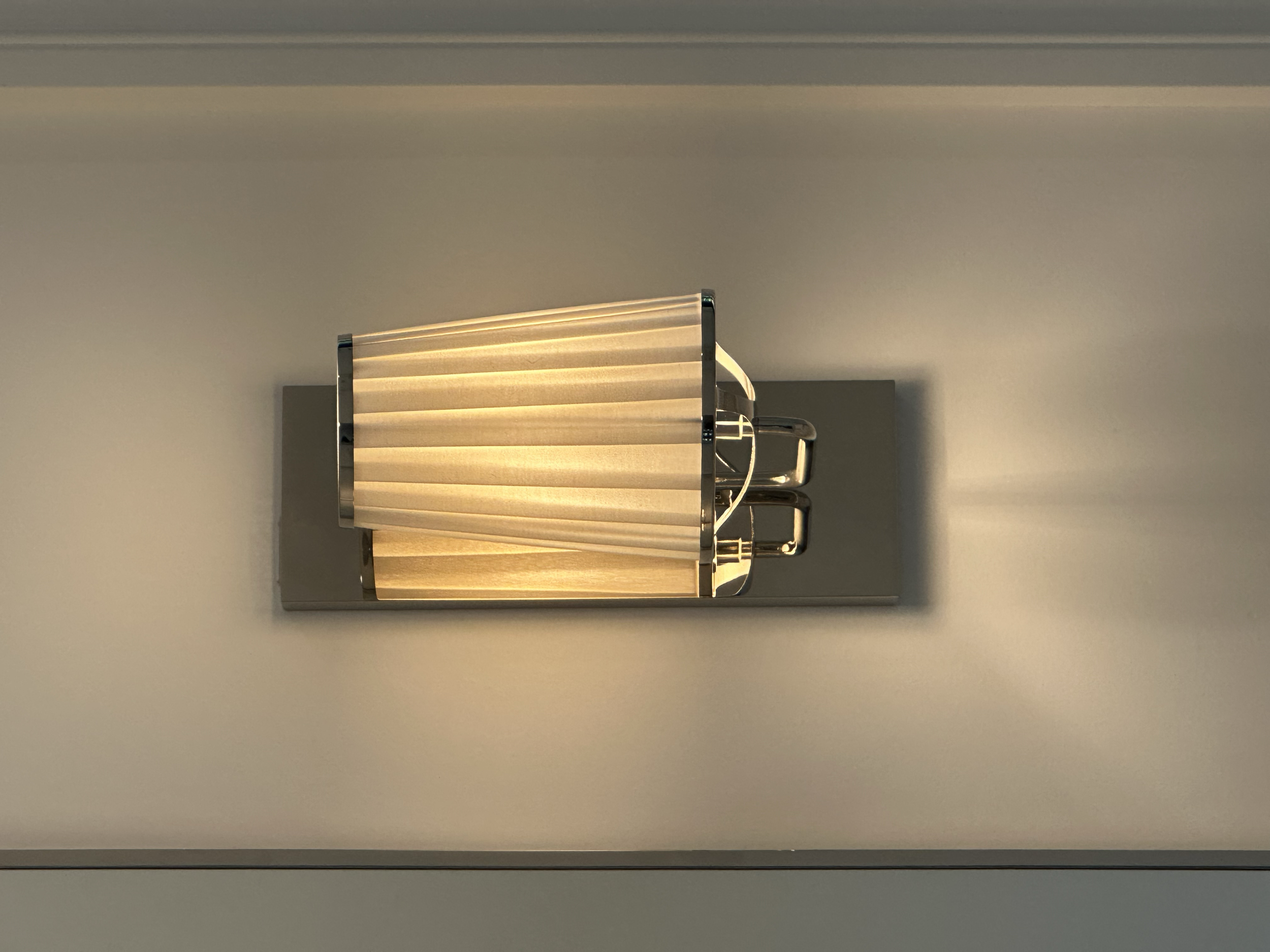 A modern ceiling light fixture with a rectangular shape, featuring horizontal beige panels framed in metallic trim, mounted on a light-colored ceiling.