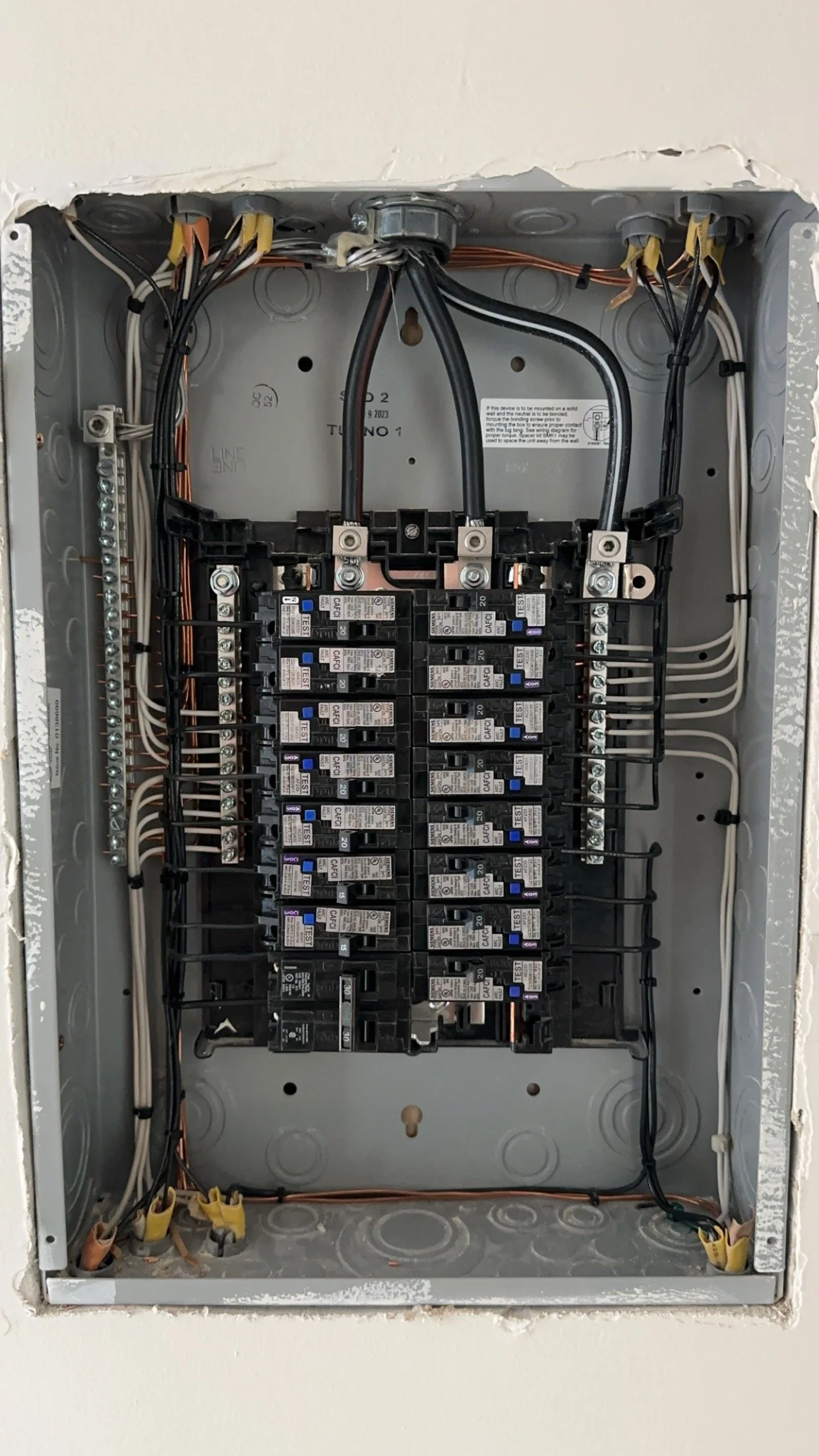 Electrical breaker panel with multiple circuit breakers and wiring.