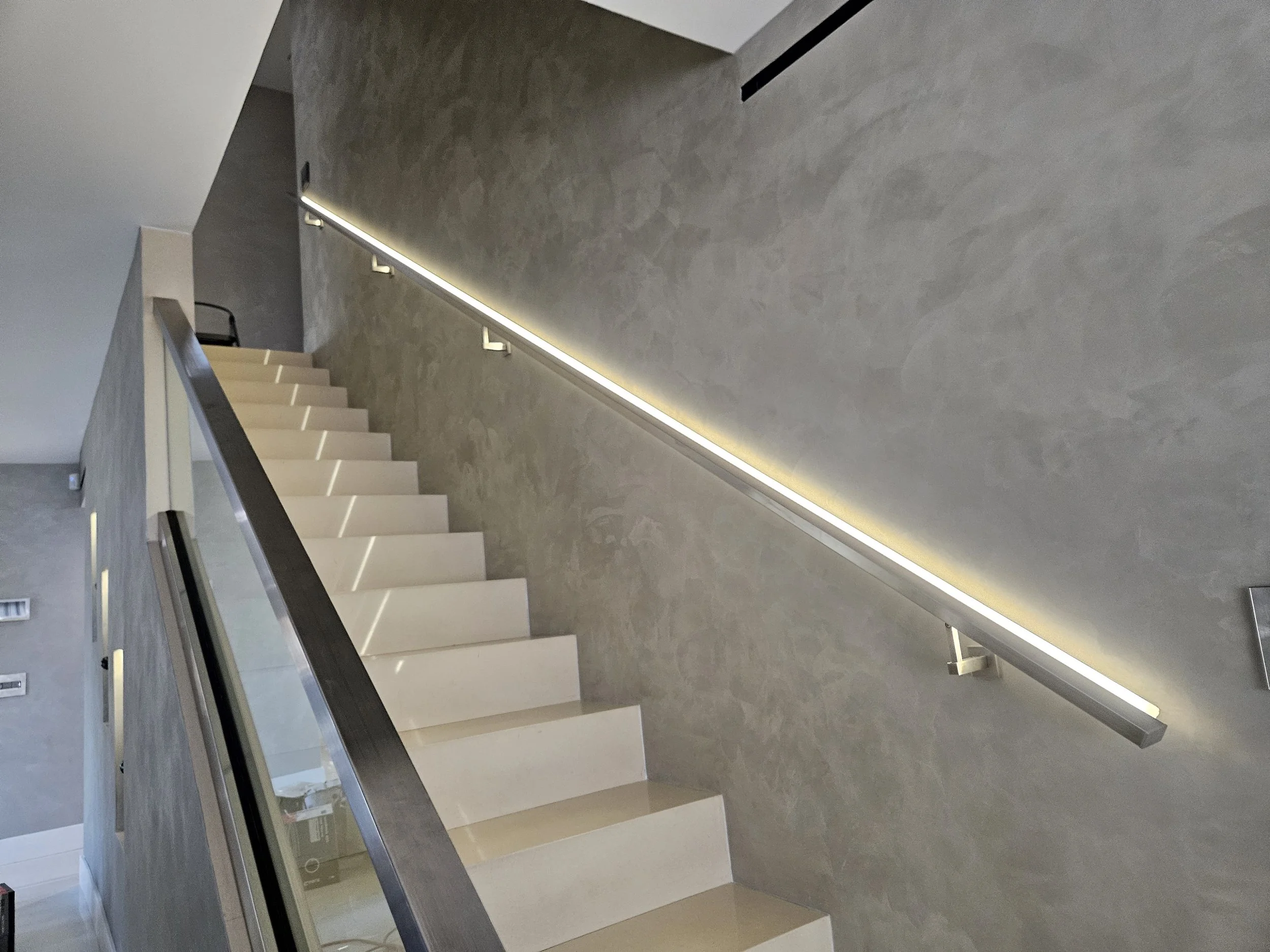 Interior view of a modern building staircase with illuminated handrails and minimalist design.