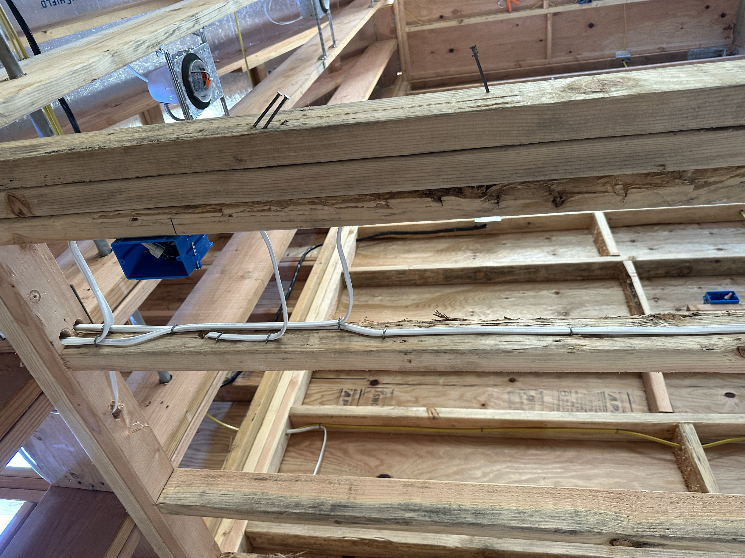 Interior view of a wooden construction site with framing, electrical wiring, and plumbing fixtures installed.