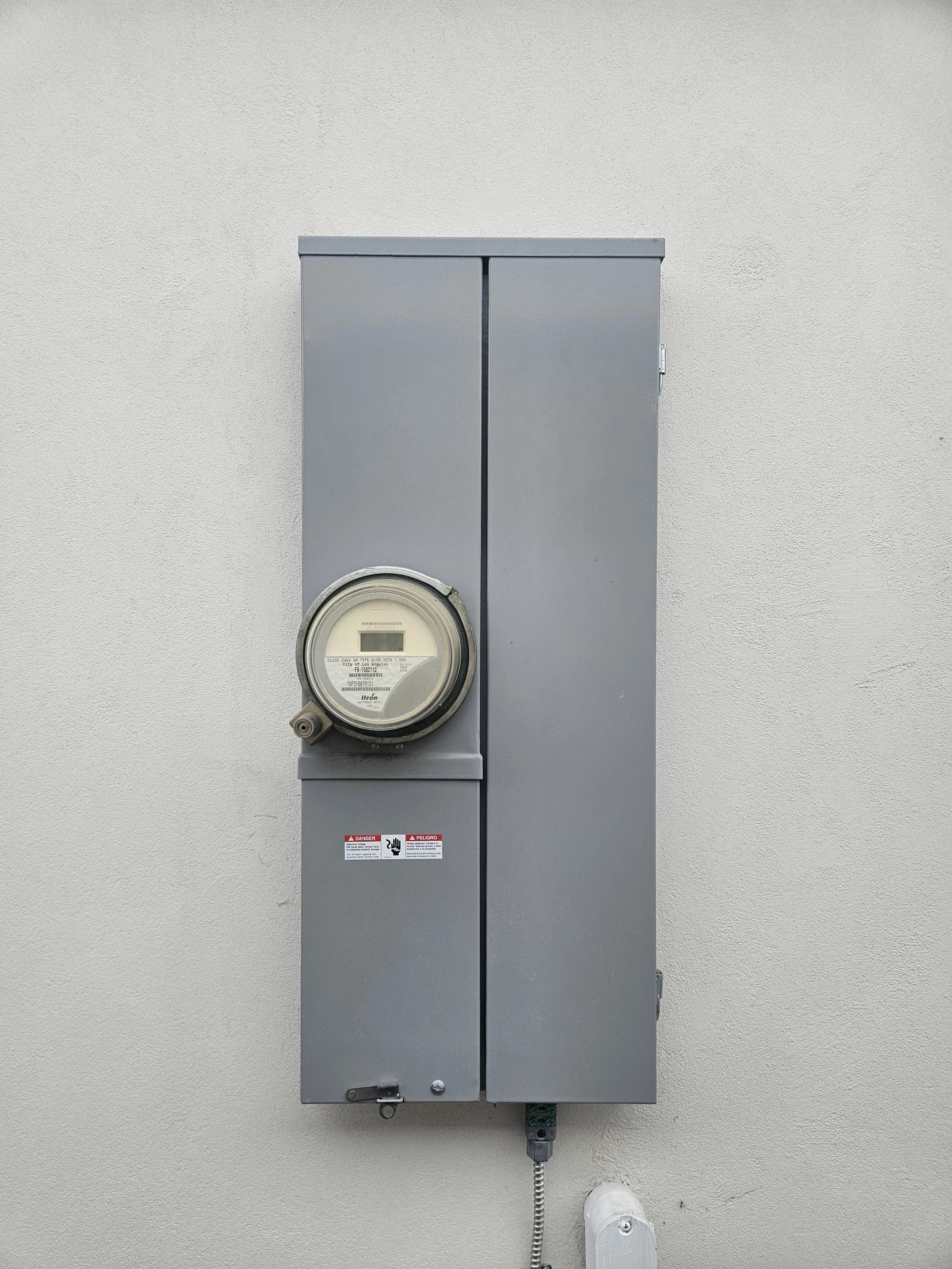 Electric meter and electrical box mounted on a white wall.