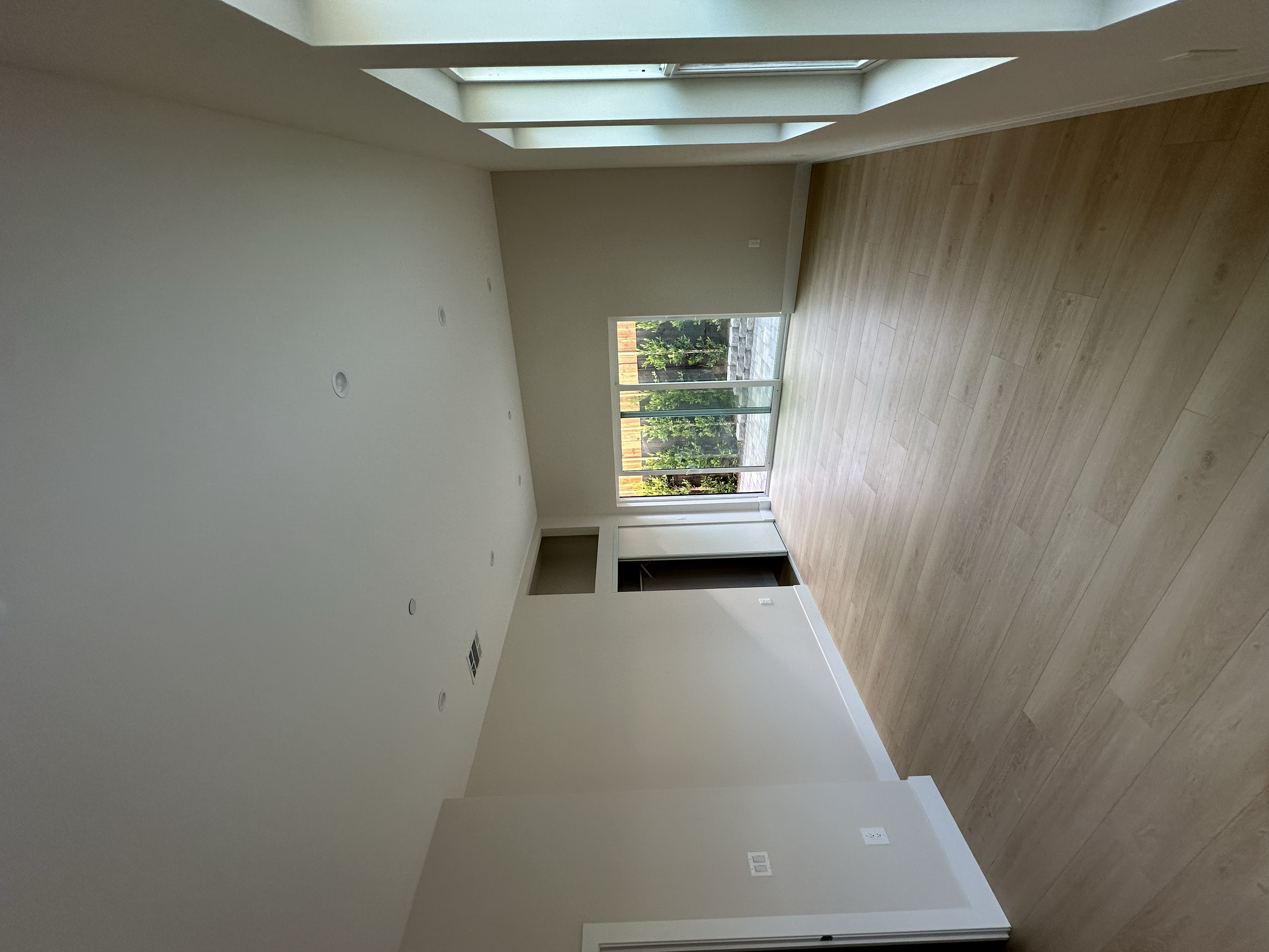 Empty room with large sliding glass doors leading to an outdoor patio with greenery.