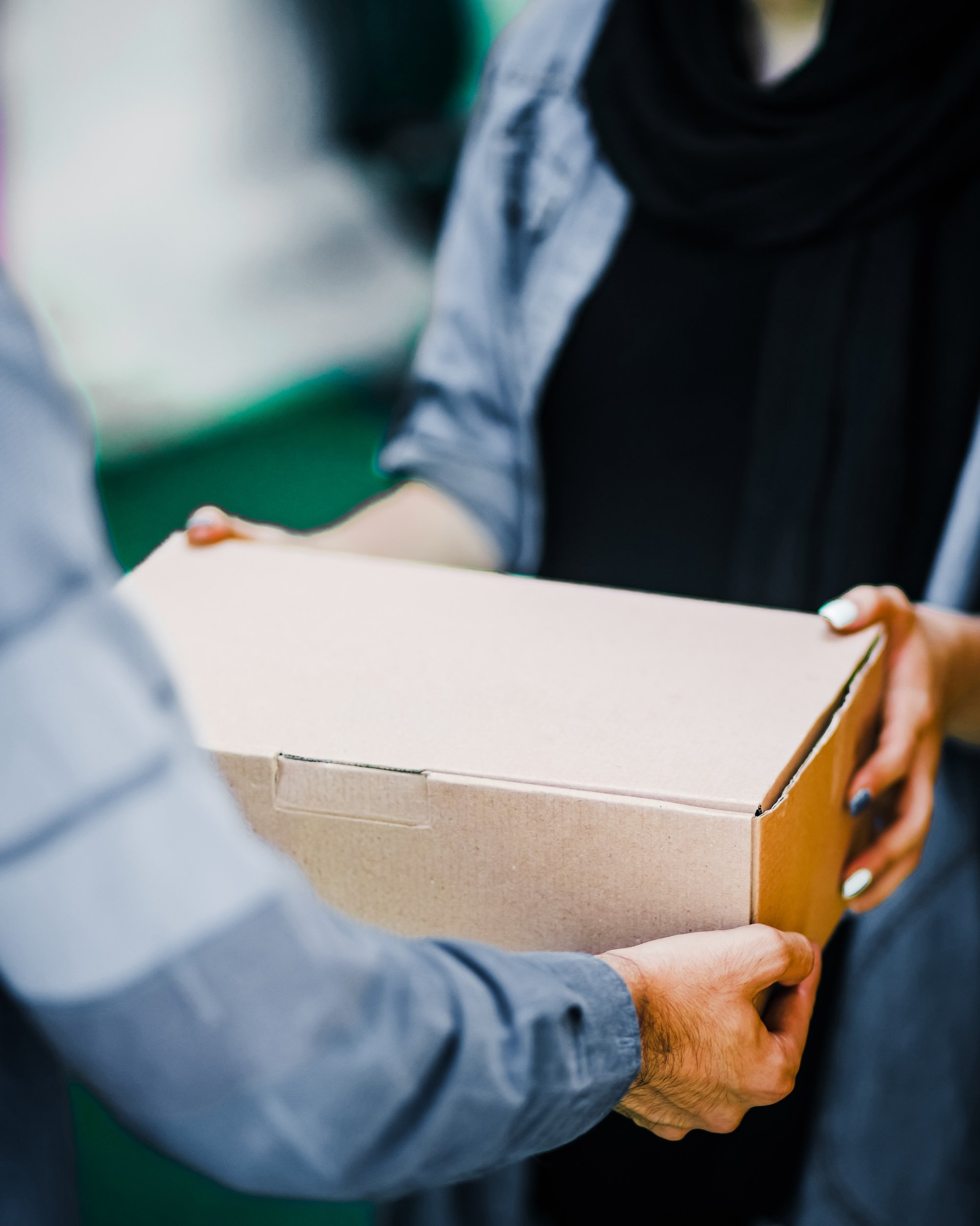 Photo of a Reliable Delivery Driver Handing a Package in a Cardboard Box to a Happy Customer