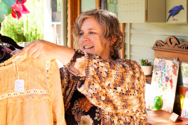 Woman looks at vintage clothes on a hanger.