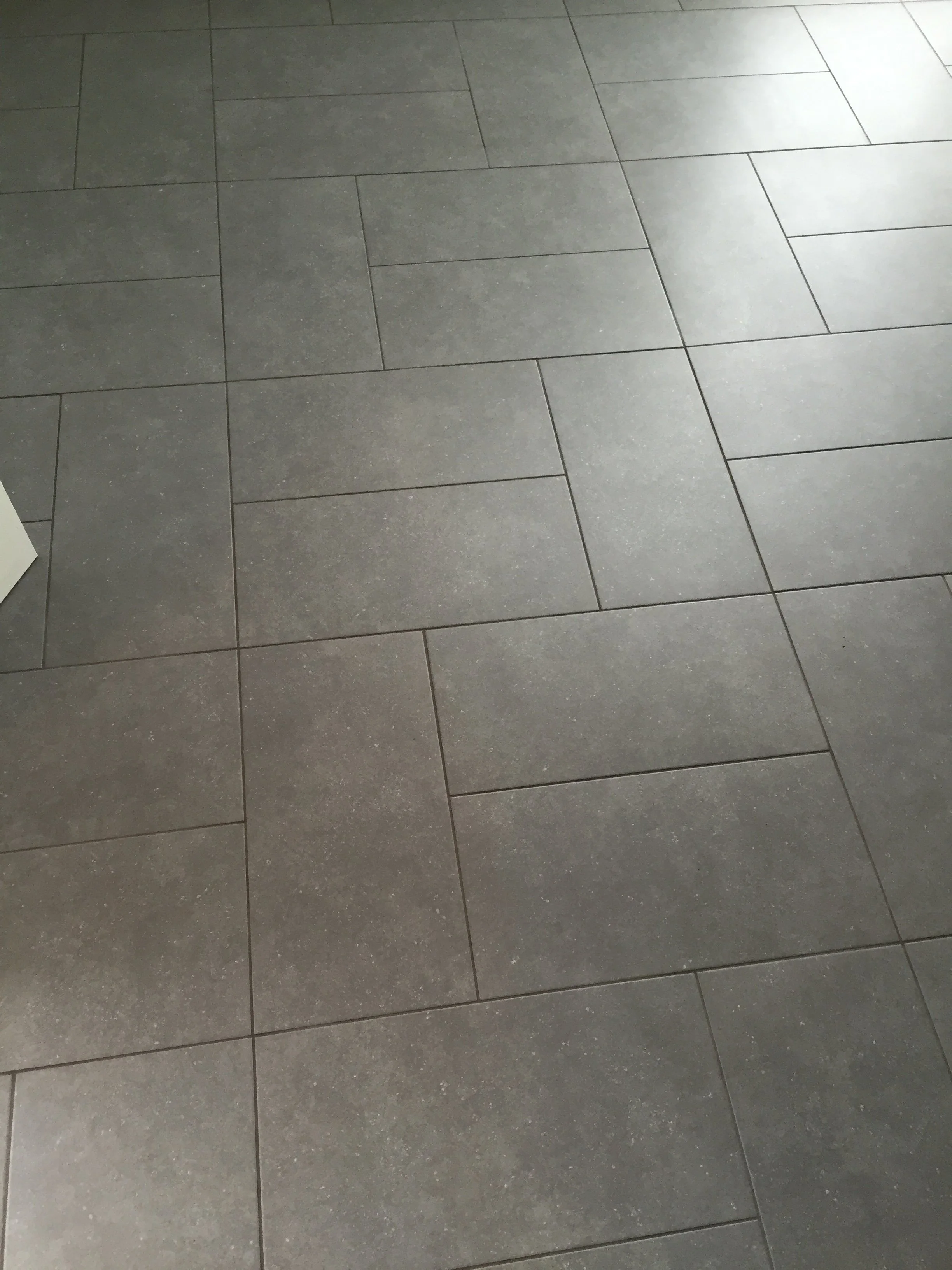 A floor made of rectangular gray tiles with a matte finish, arranged in a staggered pattern.