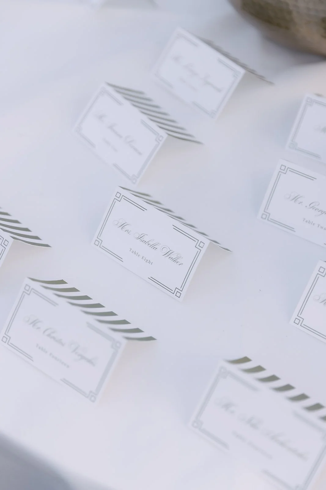Wedding reception place cards on a table, including one for Mrs. Isabella Walker, Table Eight.