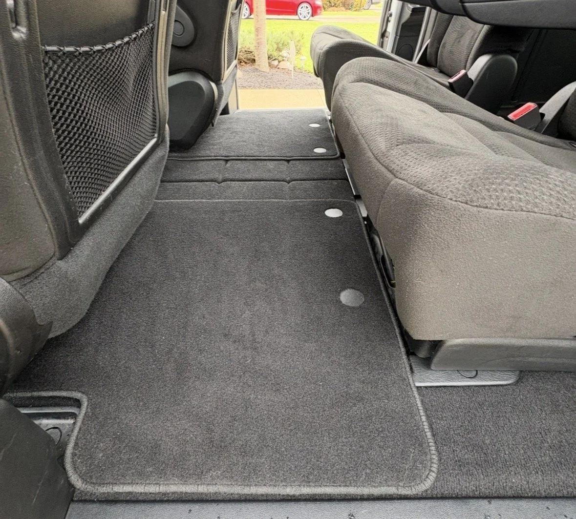 Interior of a vehicle showing folded rear seats and a flat cargo area with a carpeted floor.