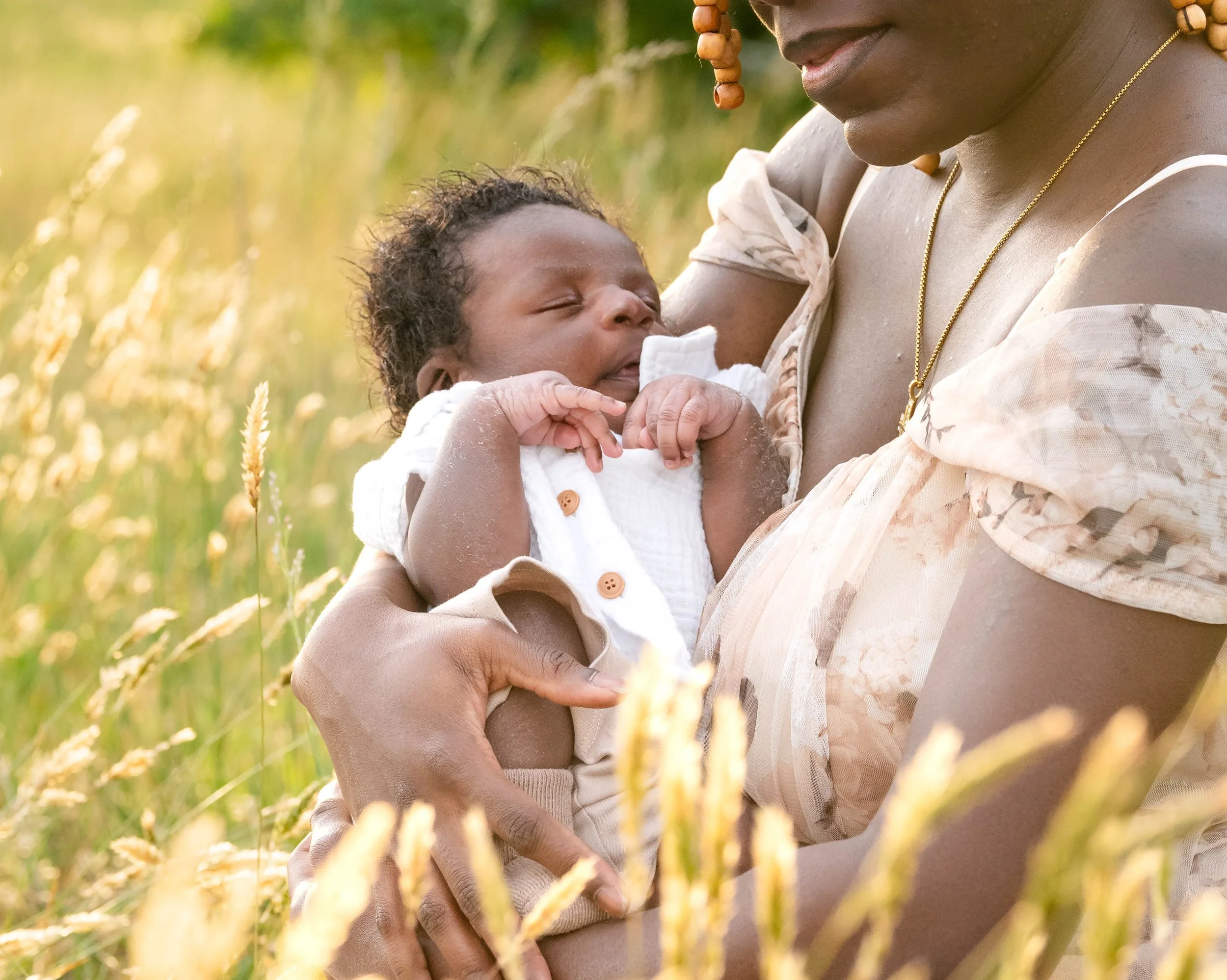 A woman holding a sleeping baby in a field of tall grass or wheat