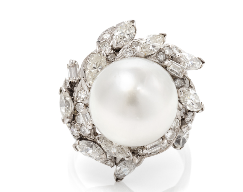 Ring with a large pearl at the center, surrounded by numerous diamonds in a floral pattern.