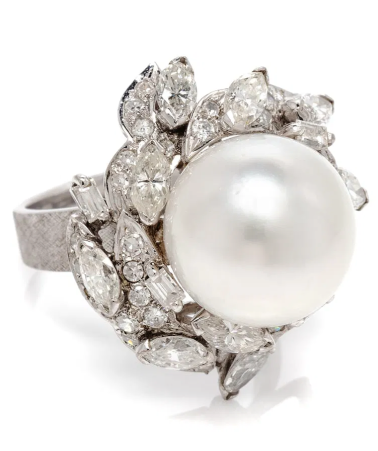 Ring with large pearl center surrounded by diamonds and clear gemstones.