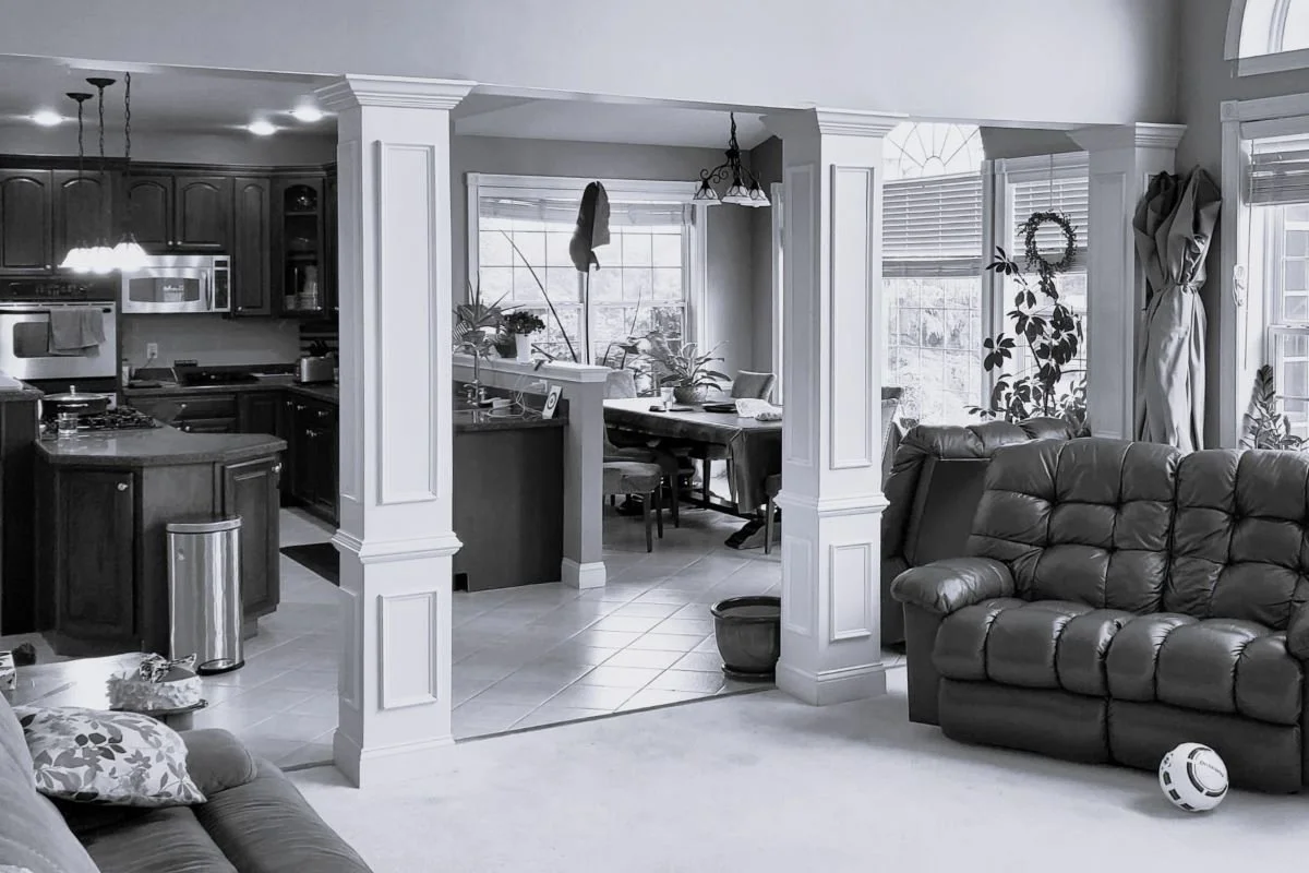 Before photo of the kitchen, dining area, and family room in a 1990s developer home in Mullica Hill, New Jersey, showing ornamental columns and disconnected living spaces before renovation.