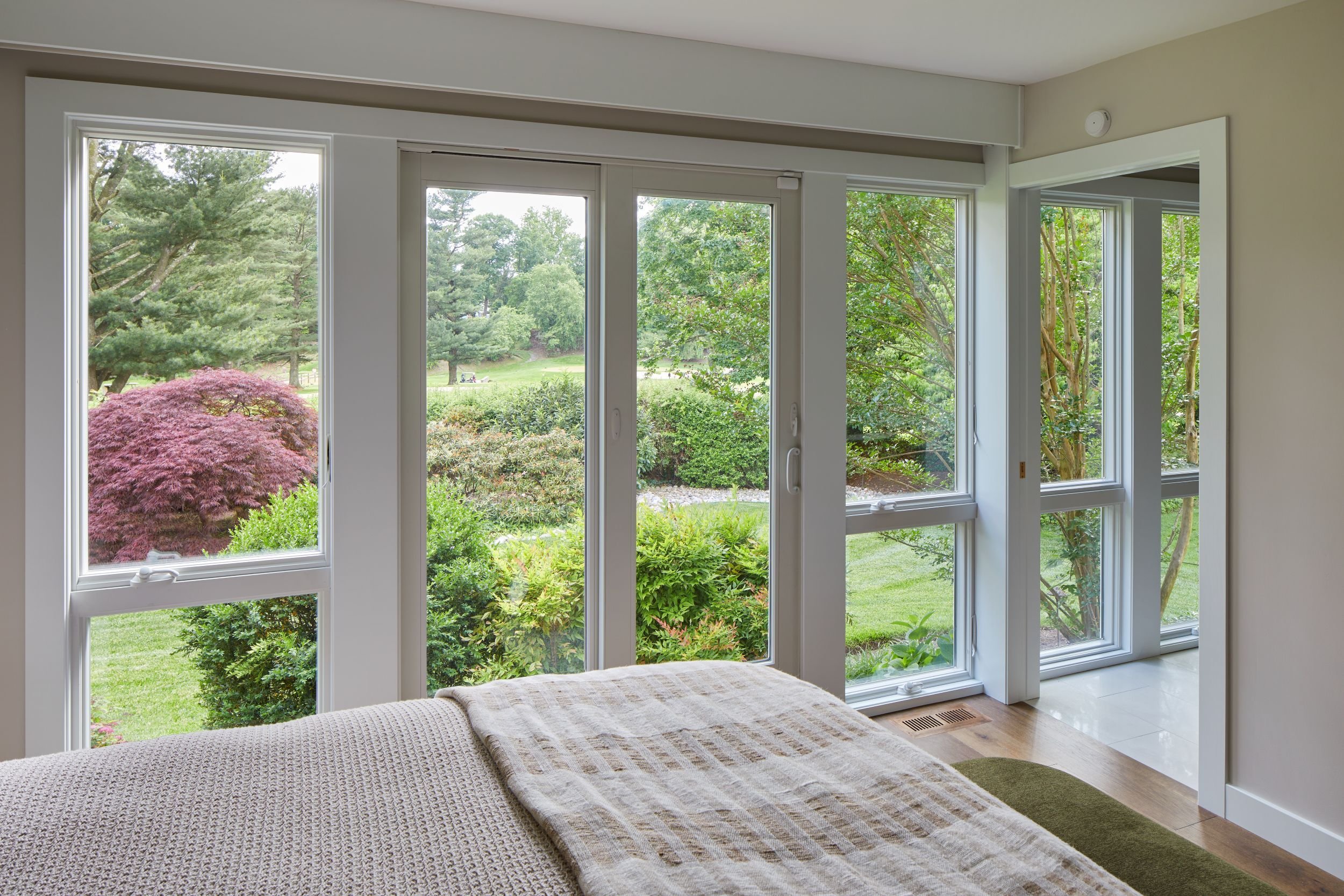 Renovated primary bedroom mid-century modern home Cherry Hill NJ — floor-to-ceiling windows golf course views rear yard garden Japanese maple landscaping direct outdoor connection J Reinert Architecture