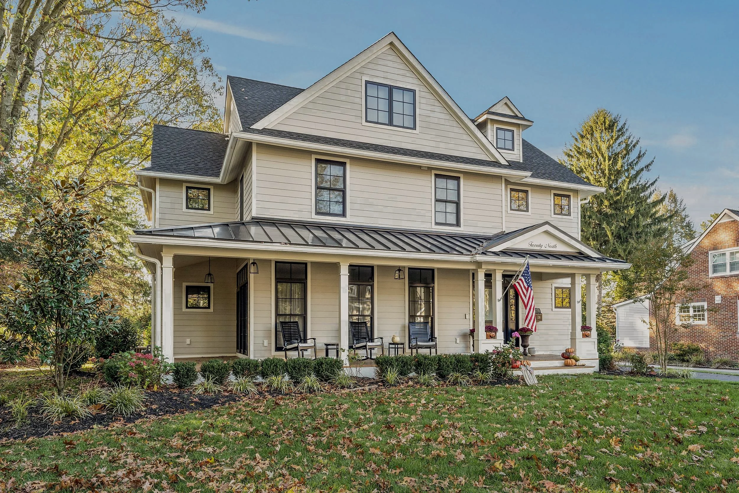 Front elevation of a new transitional two-and-a-half-story home with a deep covered porch, standing-seam metal porch roof, and black windows, Haddonfield, NJ.