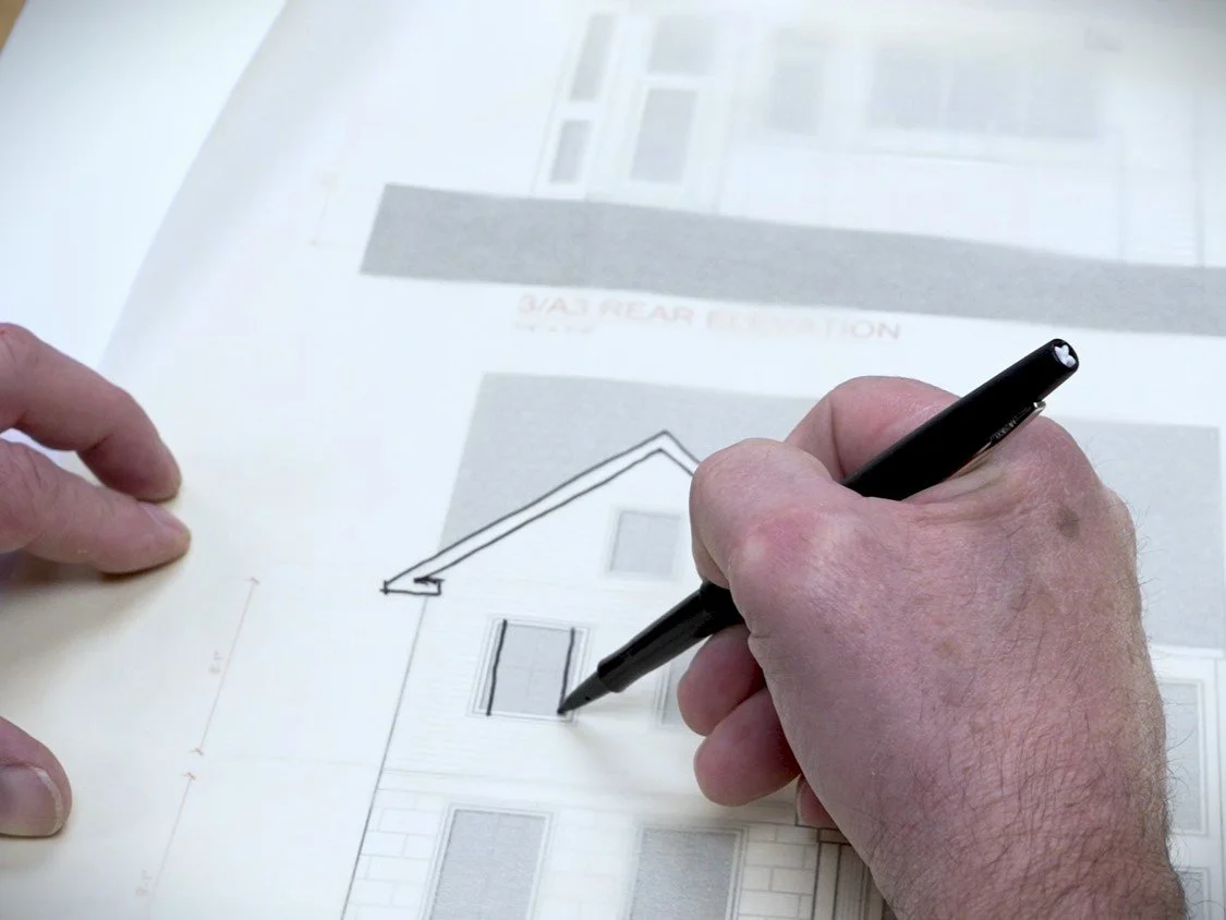 Architect sketching over residential elevation drawings during the early design process at J Reinert Architecture