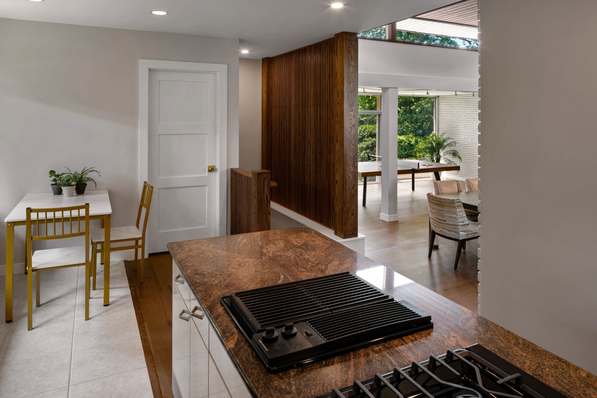 Renovated mid-century modern kitchen in Cherry Hill, NJ with open connection to dining room, oak slat screen wall, clerestory light, wood flooring, and large kitchen island.