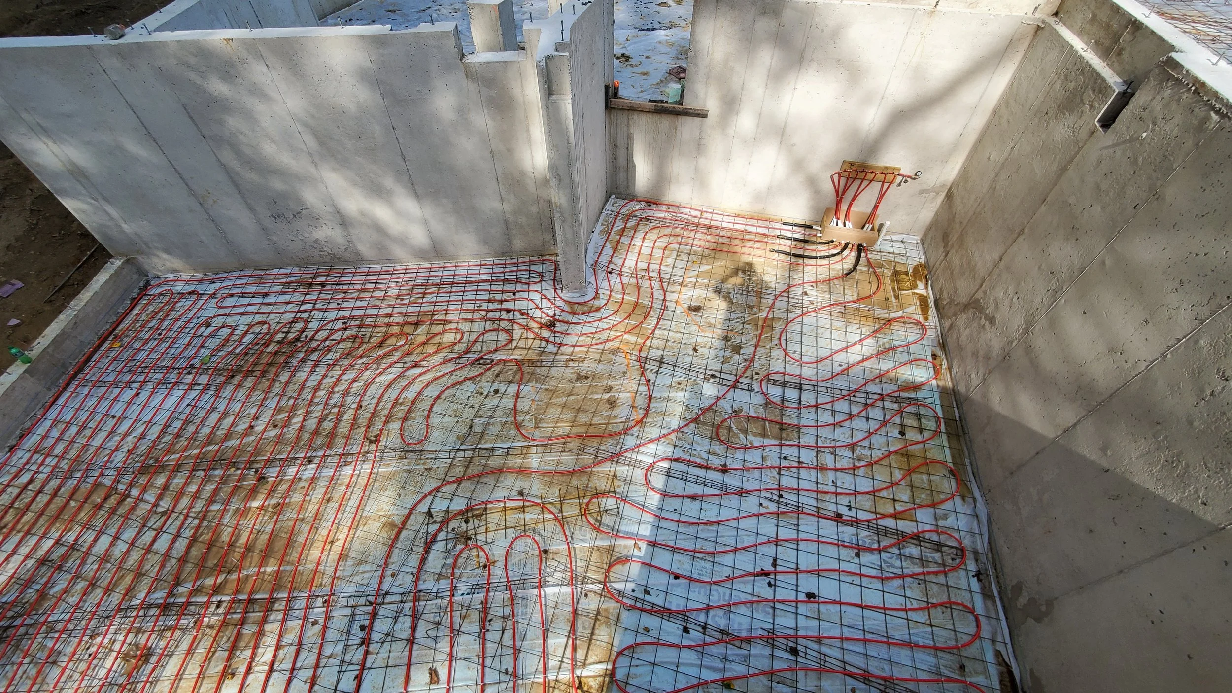 Radiant floor heating tubing installed over the lower level of Hadro House Haddonfield NJ before the slab pour — invisible comfort built into the aging-in-place design