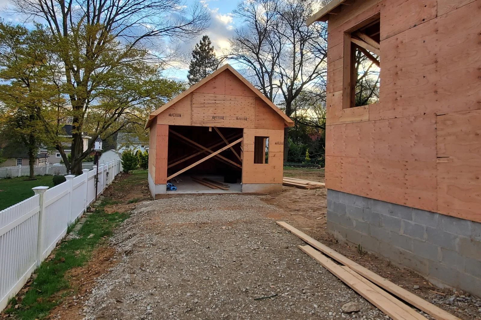 April 2020 — detached garage pavilion framing from rear of property at 310 9th Avenue Haddon Heights NJ showing gable framing, full rear yard open between garage and house, neighboring white fence visible at left — J Reinert Architecture