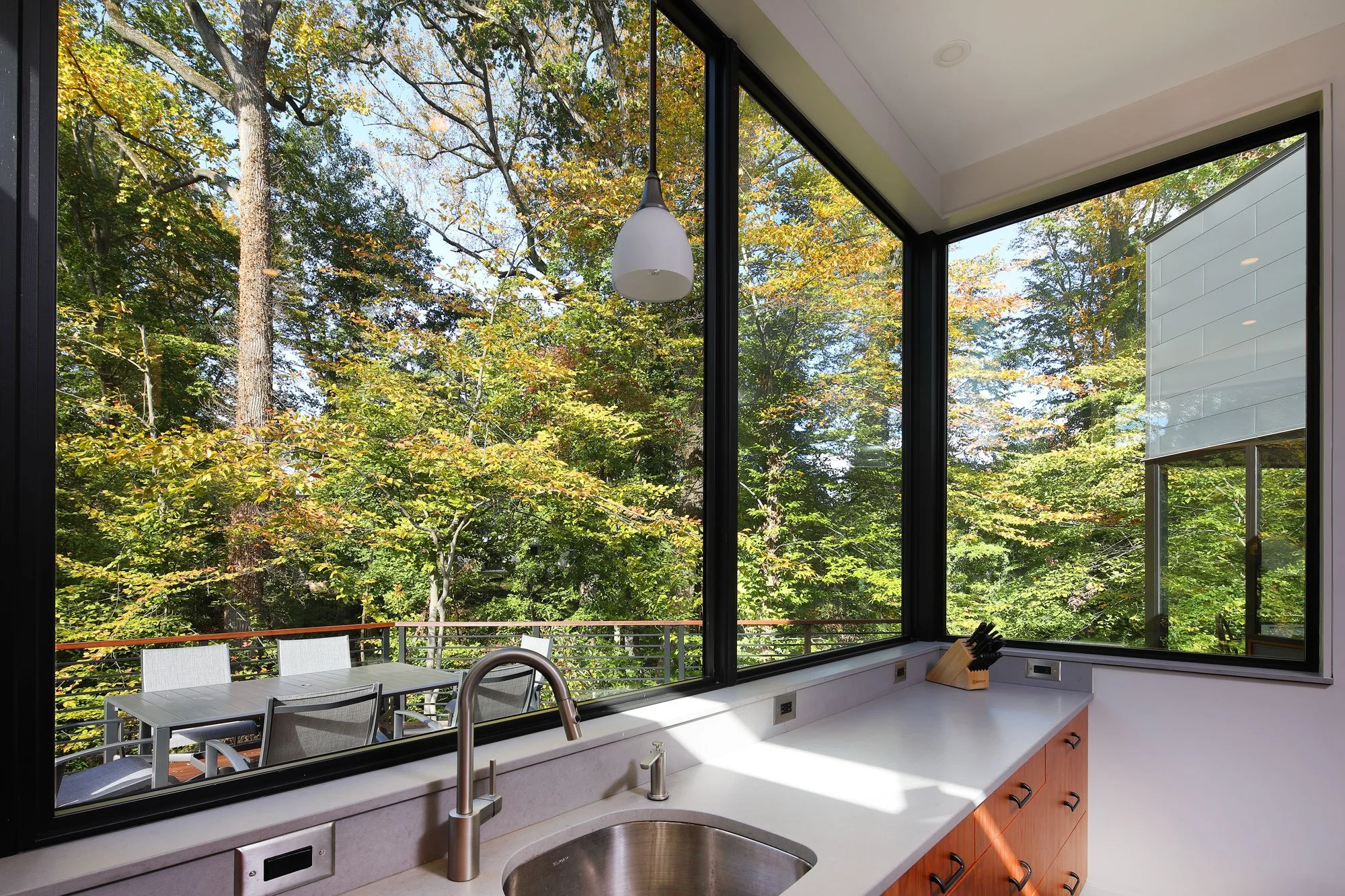 Corner kitchen window over the sink at Hadro House Haddonfield NJ — the owners' requested view from the prep area, looking straight into the forest canopy