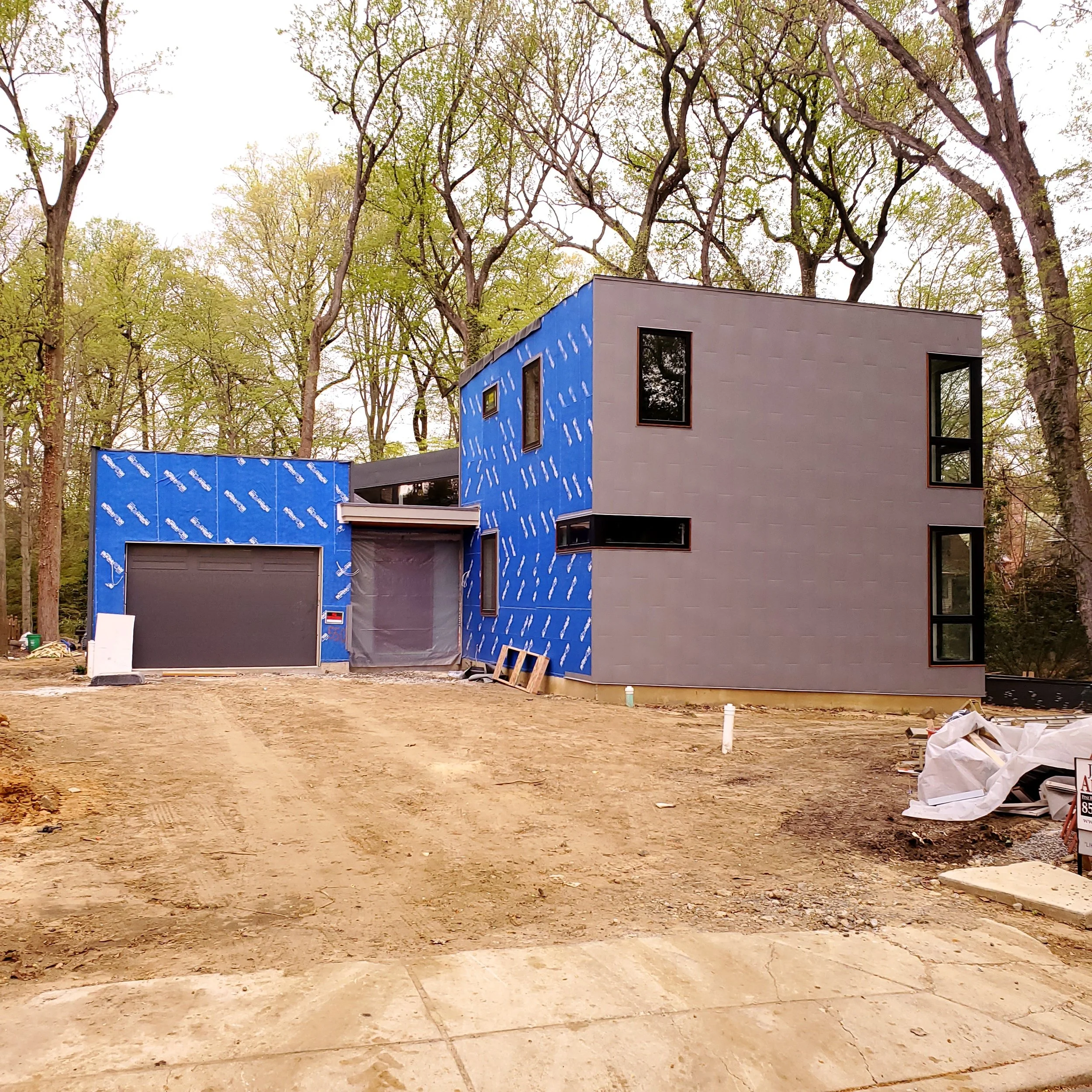 Recyclable textured steel panel cladding partially installed over the weather barrier at Hadro House Haddonfield NJ, April 2021 — the dinosaur-scale skin going on volume by volume