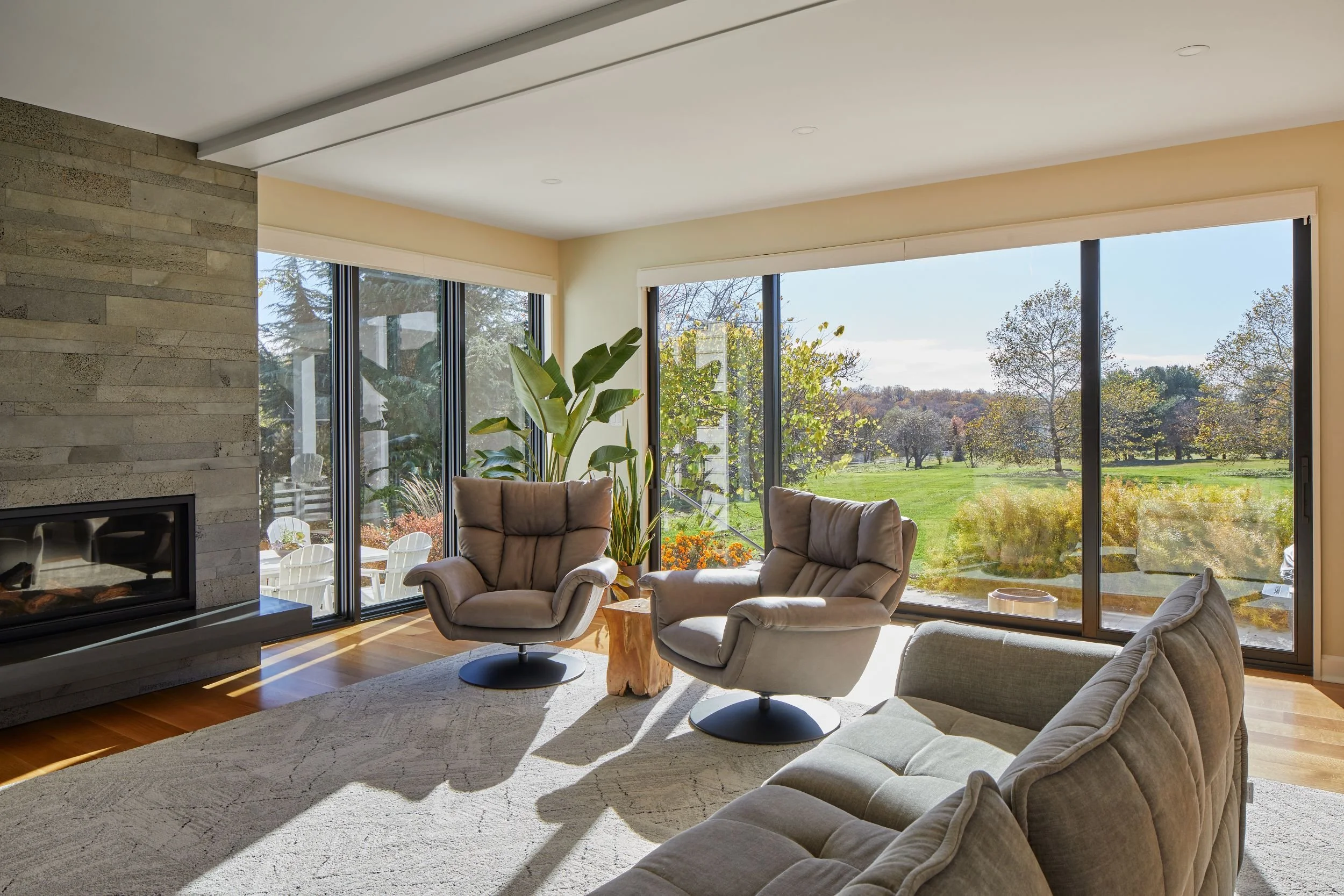 Renovated living room in a Mullica Hill, New Jersey home with large sliding glass doors, field views, a lava-stone fireplace, and indoor-outdoor connection.