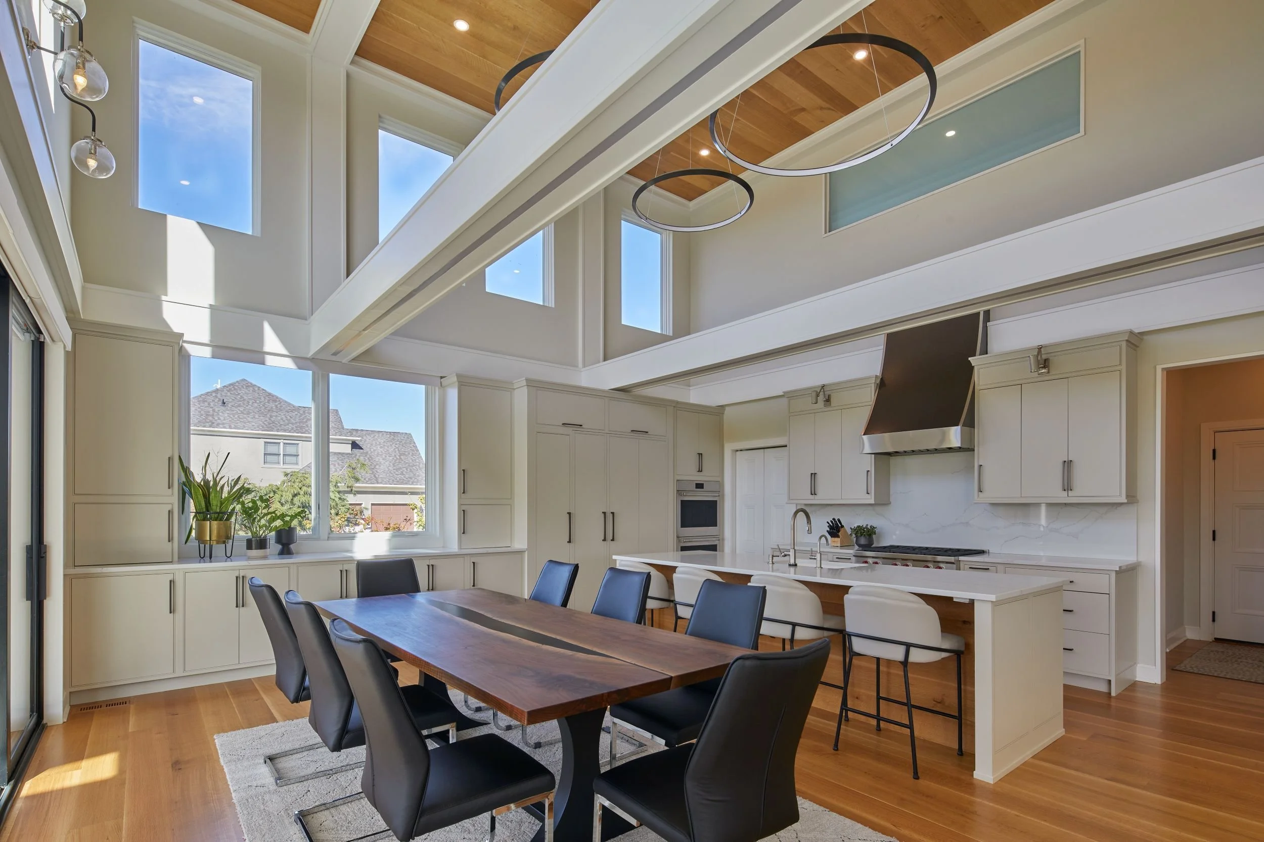 Renovated kitchen and dining area in a Mullica Hill, New Jersey home with a double-height ceiling, clerestory windows, white oak floors, and contemporary structural grid.