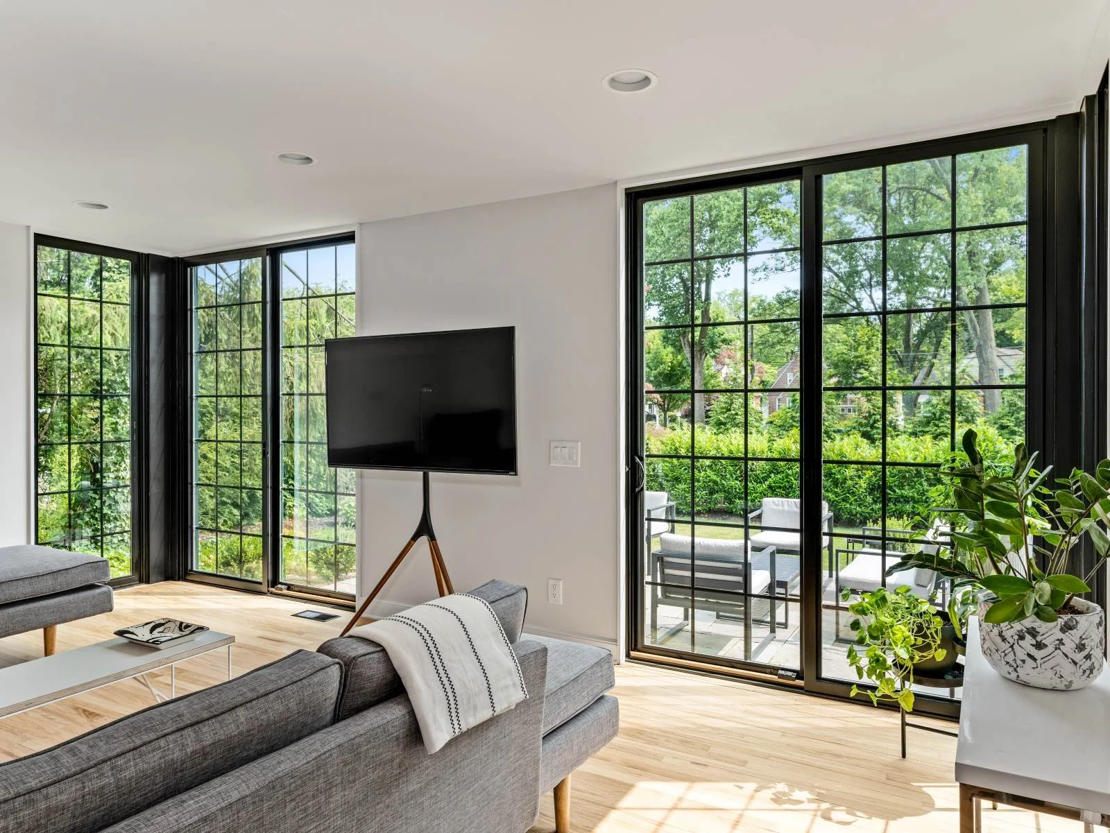 Renovated family room Haddonfield NJ floor-to-ceiling Pella fiberglass grid windows two walls corner dissolves garden views exposed brick chimney J Reinert Architecture