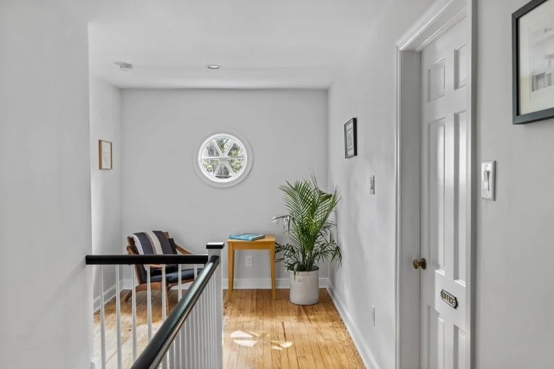 Renovated staircase second floor hallway Haddonfield NJ circle window reclaimed black metal rail white oak treads light airy J Reinert Architecture