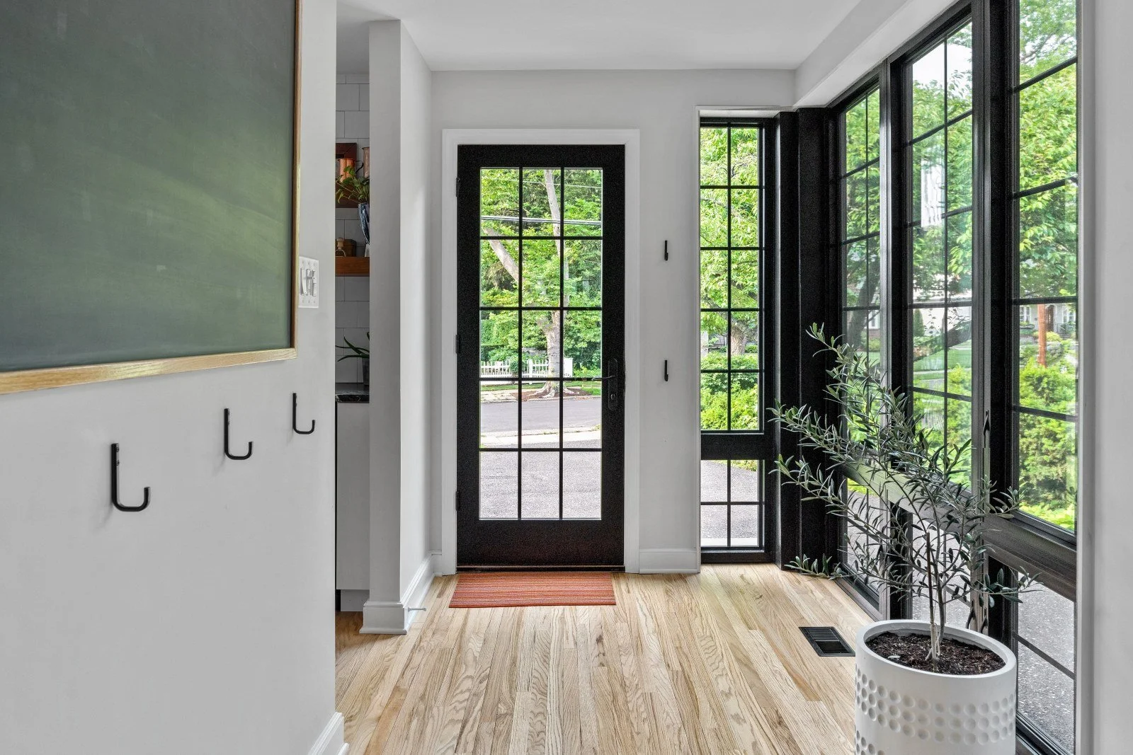 Renovated side entry mudroom Haddonfield NJ black fiberglass grid door windows light oak floor cross axis to family room J Reinert Architecture