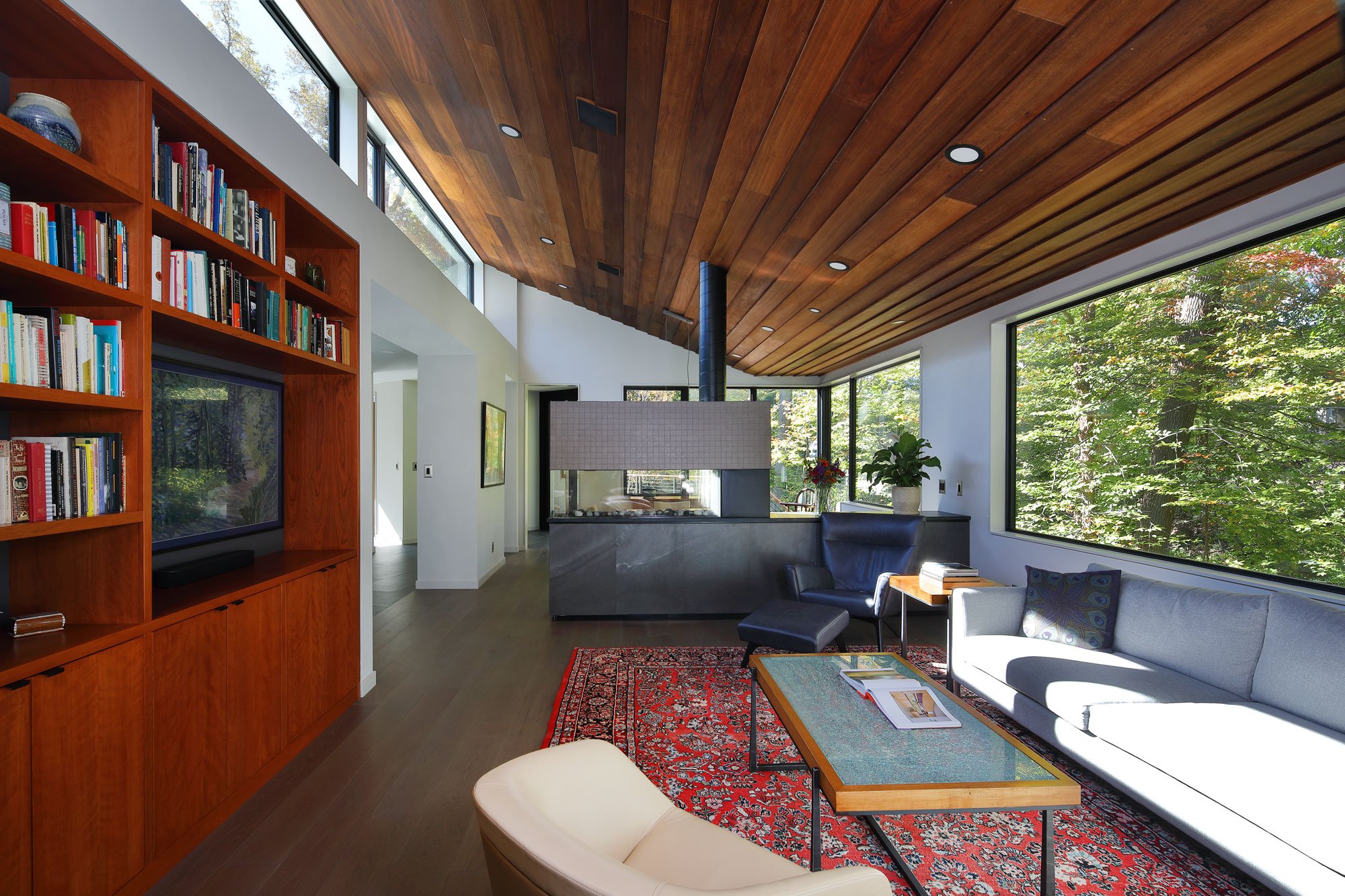 Living room of Hadro House in Haddonfield NJ with ceiling of Philippine mahogany siding salvaged from the original 1948 home, clerestory windows, and north-facing glass walls to the forest