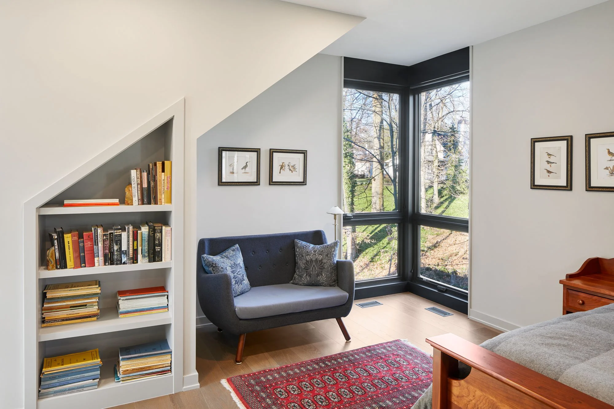 Reading nook with built-in bookshelves at Hadro House Haddonfield NJ — a quiet corner with windows to the sloping wooded site