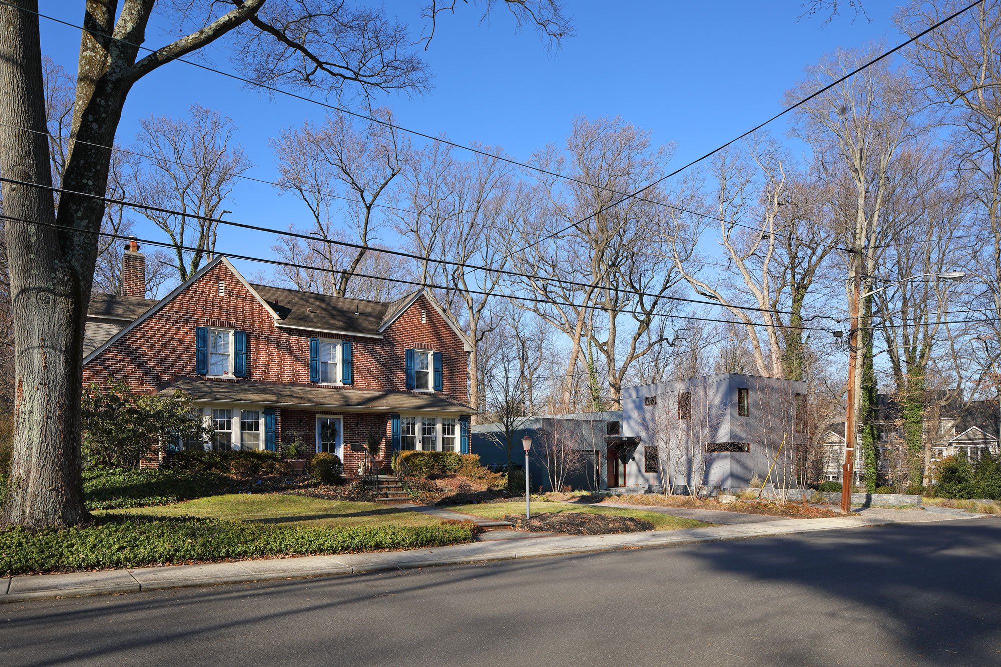 Street view in Haddonfield NJ showing Hadro House, a contemporary custom home, in context with traditional brick colonial neighbors — a neighborhood timeline of architectural styles