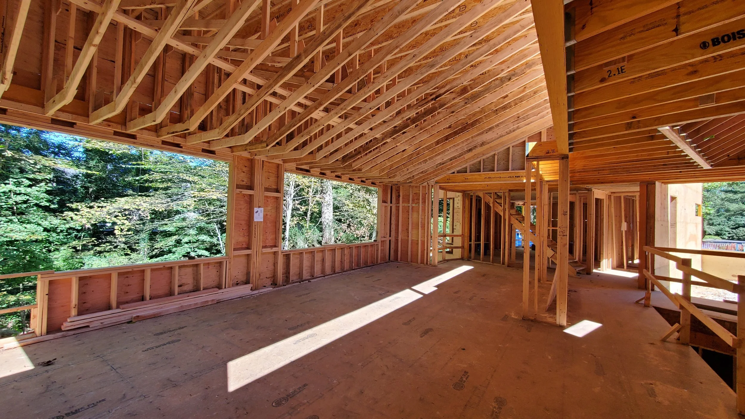 Framed main living space of Hadro House Haddonfield NJ, September 2020 — the sloping multi-plane roof structure that the salvaged mahogany ceiling would later clad, with corner openings to the woods