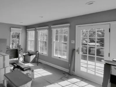 Before photo of the family room in a Haddonfield, NJ center hall colonial renovation showing existing windows, patio doors, fireplace, and limited connection to the kitchen and side entry.