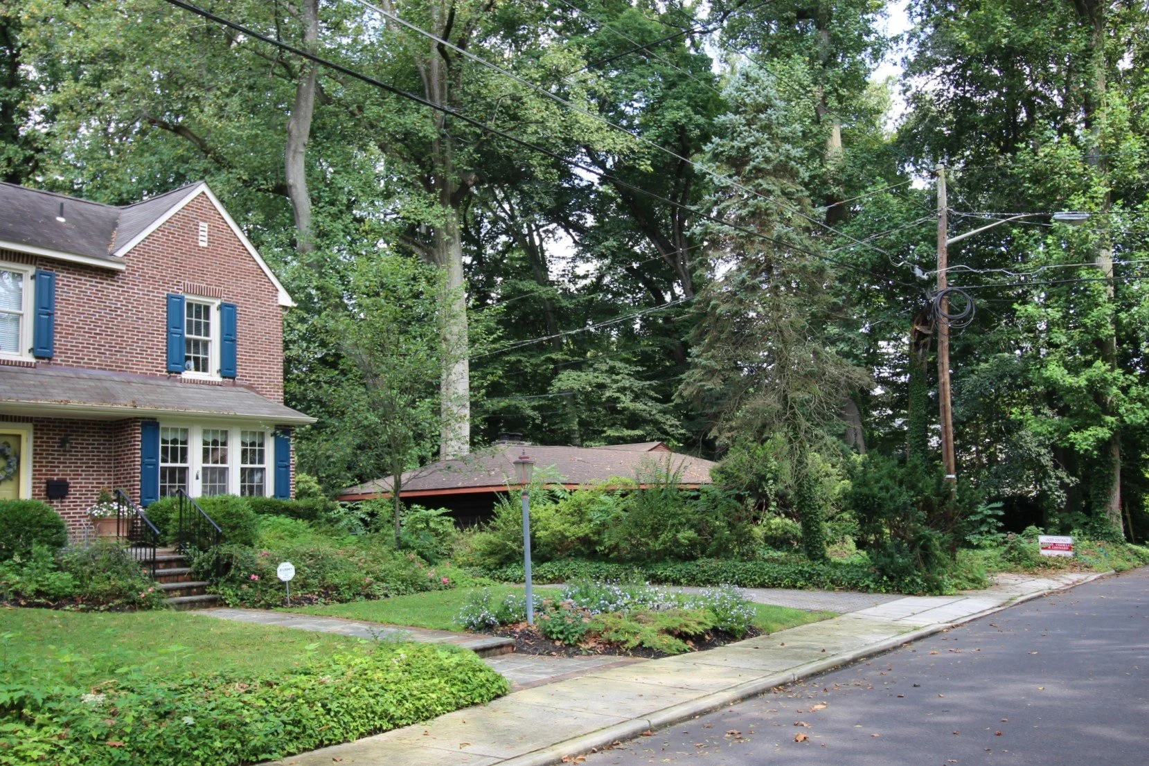 The Haddonfield NJ neighborhood street during pre-purchase site analysis for Hadro House — traditional homes and mature trees surrounding the original 1948 mid-century property