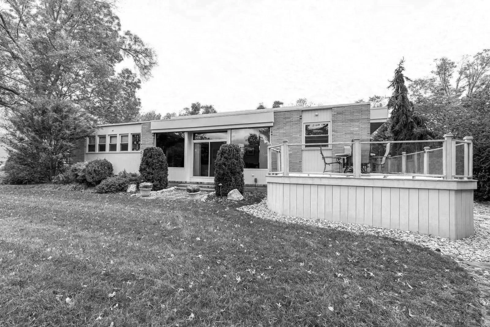 Before renovation rear exterior mid-century modern home Cherry Hill NJ — enclosed porch deteriorating composite deck stucco over original brick slider doors disconnected from yard golf course 1964
