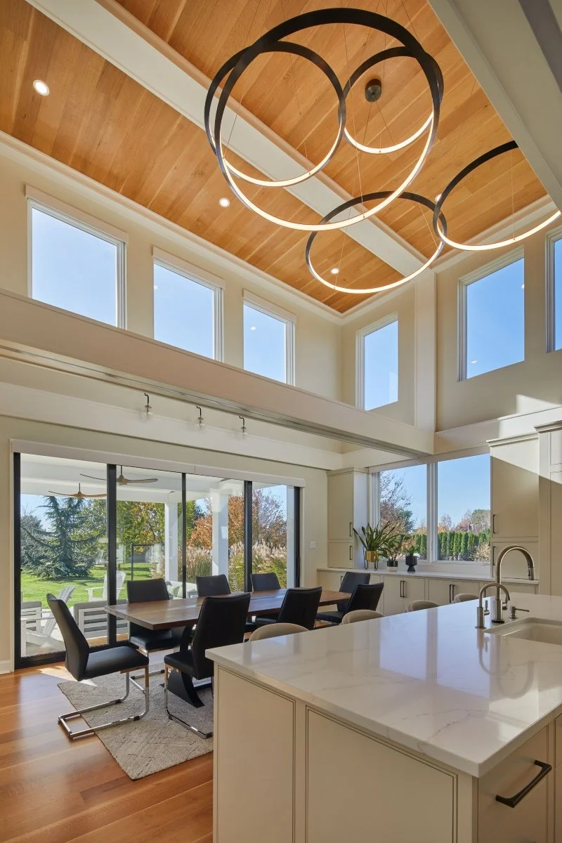 Renovated kitchen and dining area in a Mullica Hill, New Jersey home with clerestory windows, wood ceiling panels, circular pendant lights, and large sliding doors to the patio.