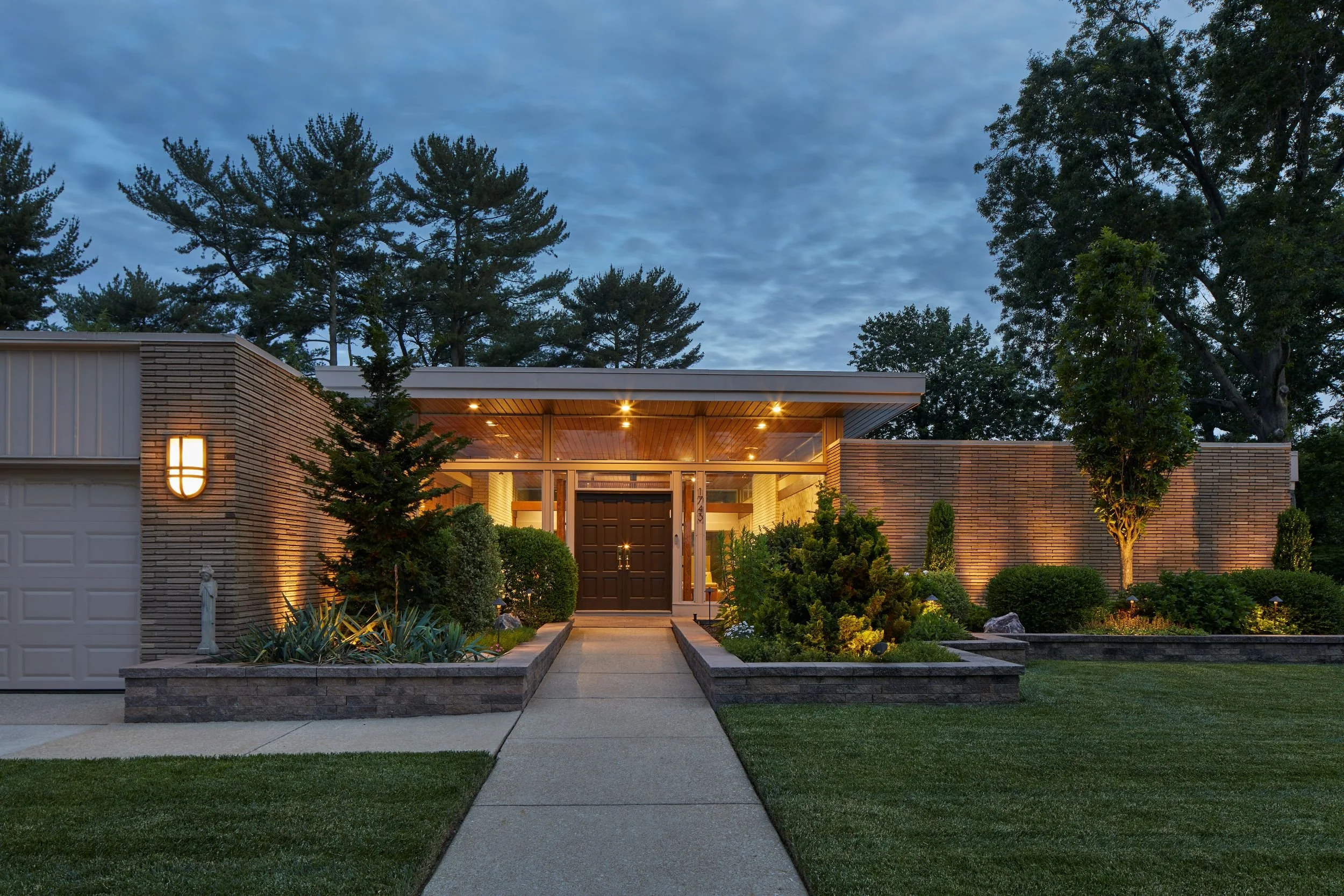 Mid-Century Modern Revisited renovation Cherry Hill NJ — 1964 mid-century modern home dusk full horizontal composition floating roof plane warm wood soffit double front door landscaped approach retaining walls J Reinert Architecture