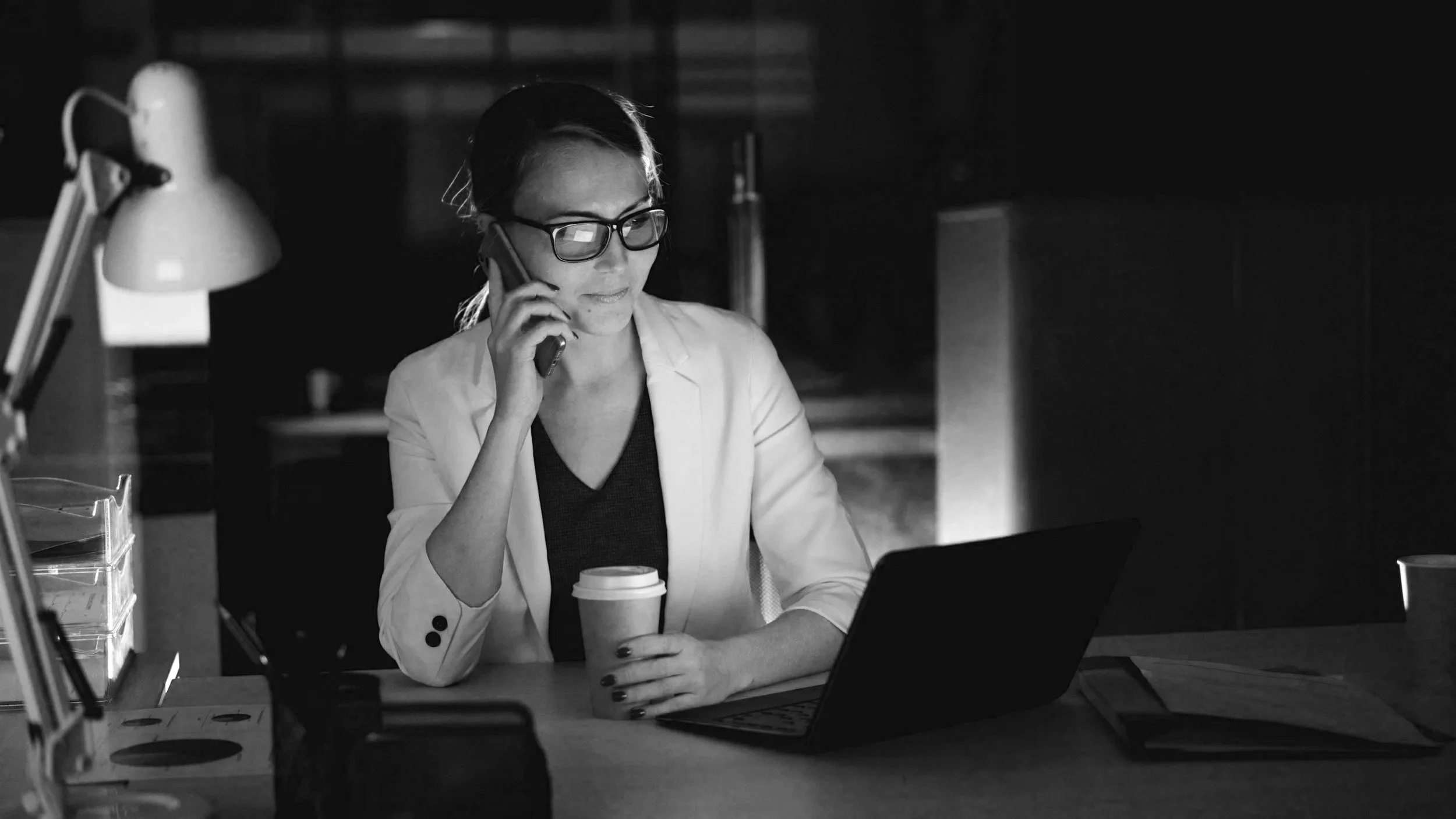 Law firm professional managing firm operations while working on a laptop and speaking on the phone.
