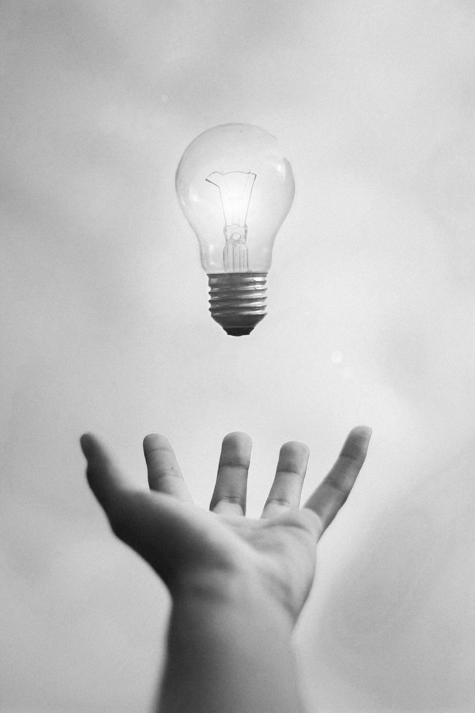 Light bulb above an open hand representing operational guidance and answers.
