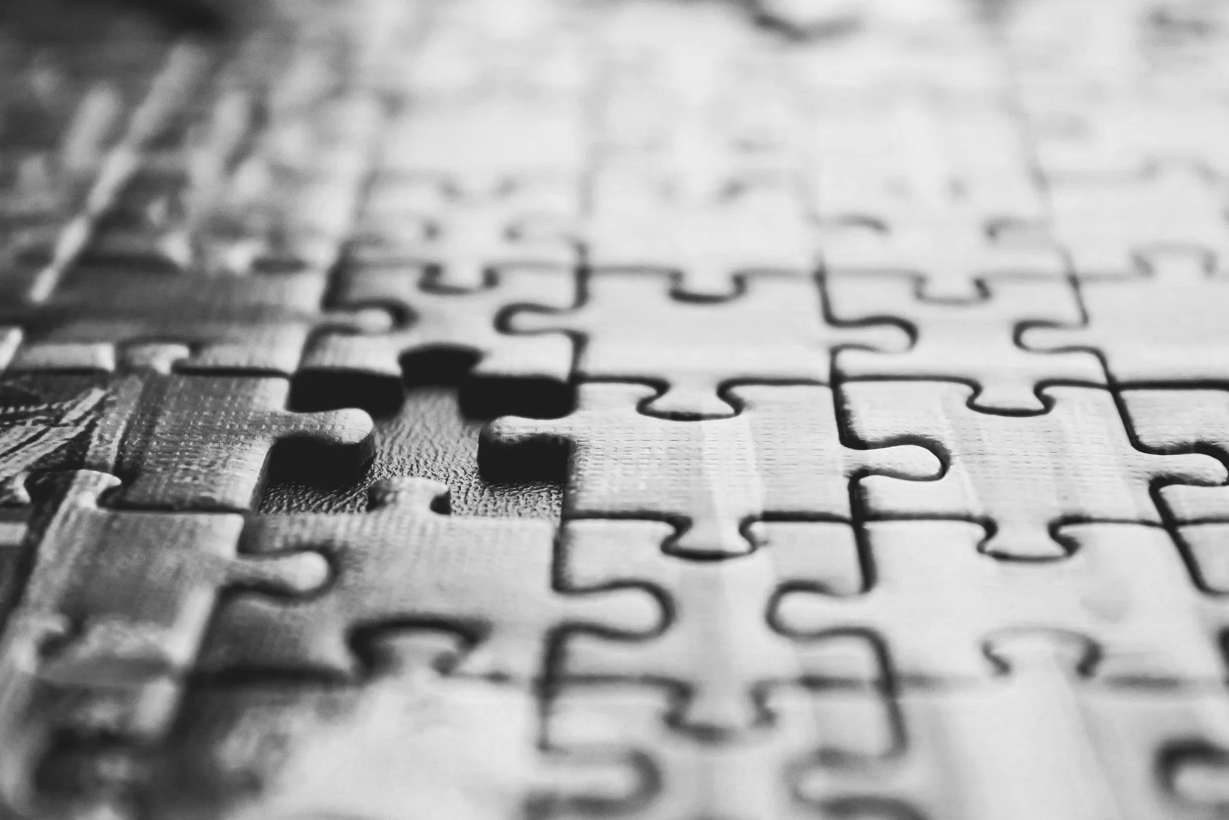 Close-up of a partially assembled jigsaw puzzle with one piece missing, representing adaptive operational solutions tailored to each law firm's needs.