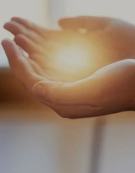 Two hands holding a glowing light source, creating a warm ambiance.