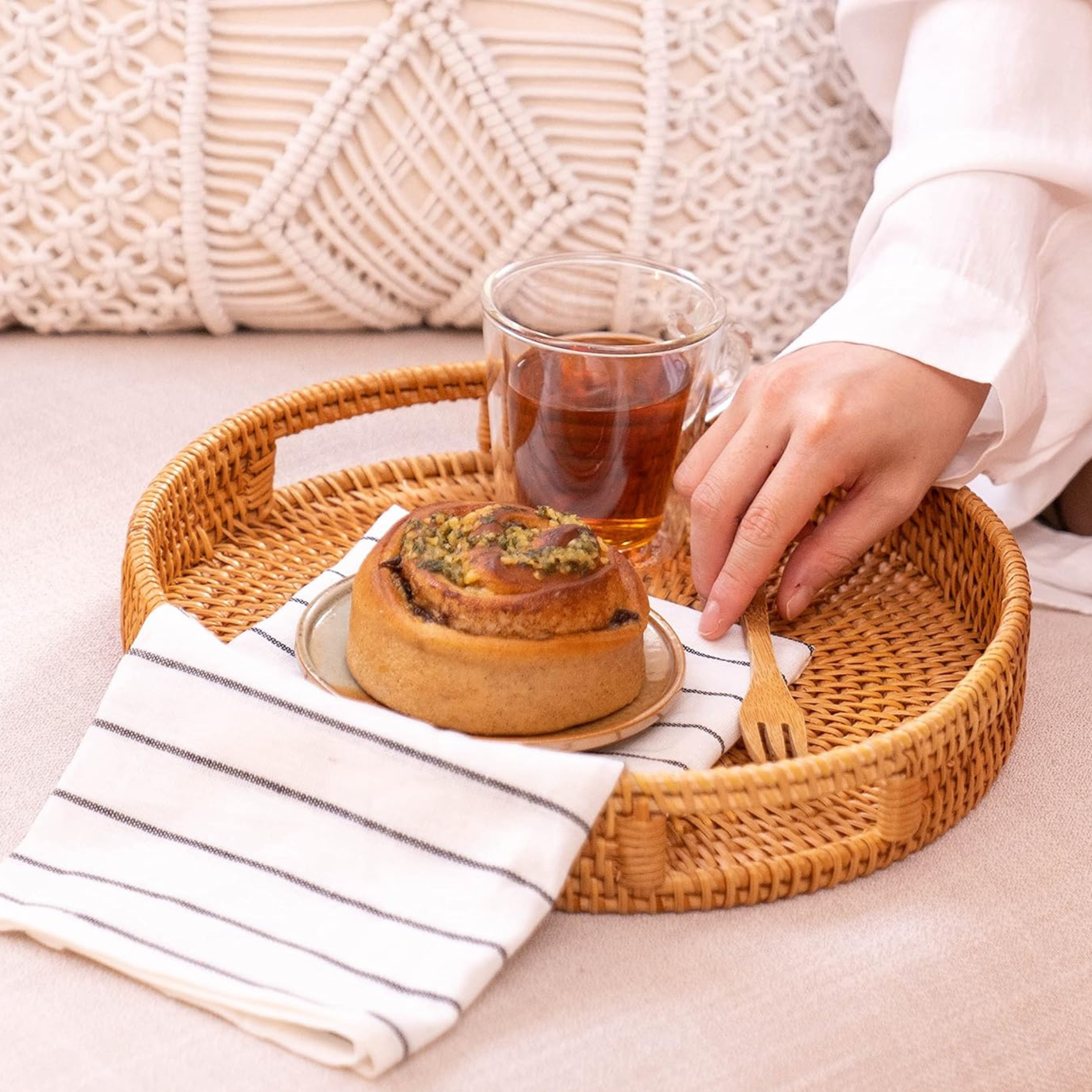 Round rattan serving tray styled on a coffee table with pastry and beverage — neutral home decor from The Alcove Edit