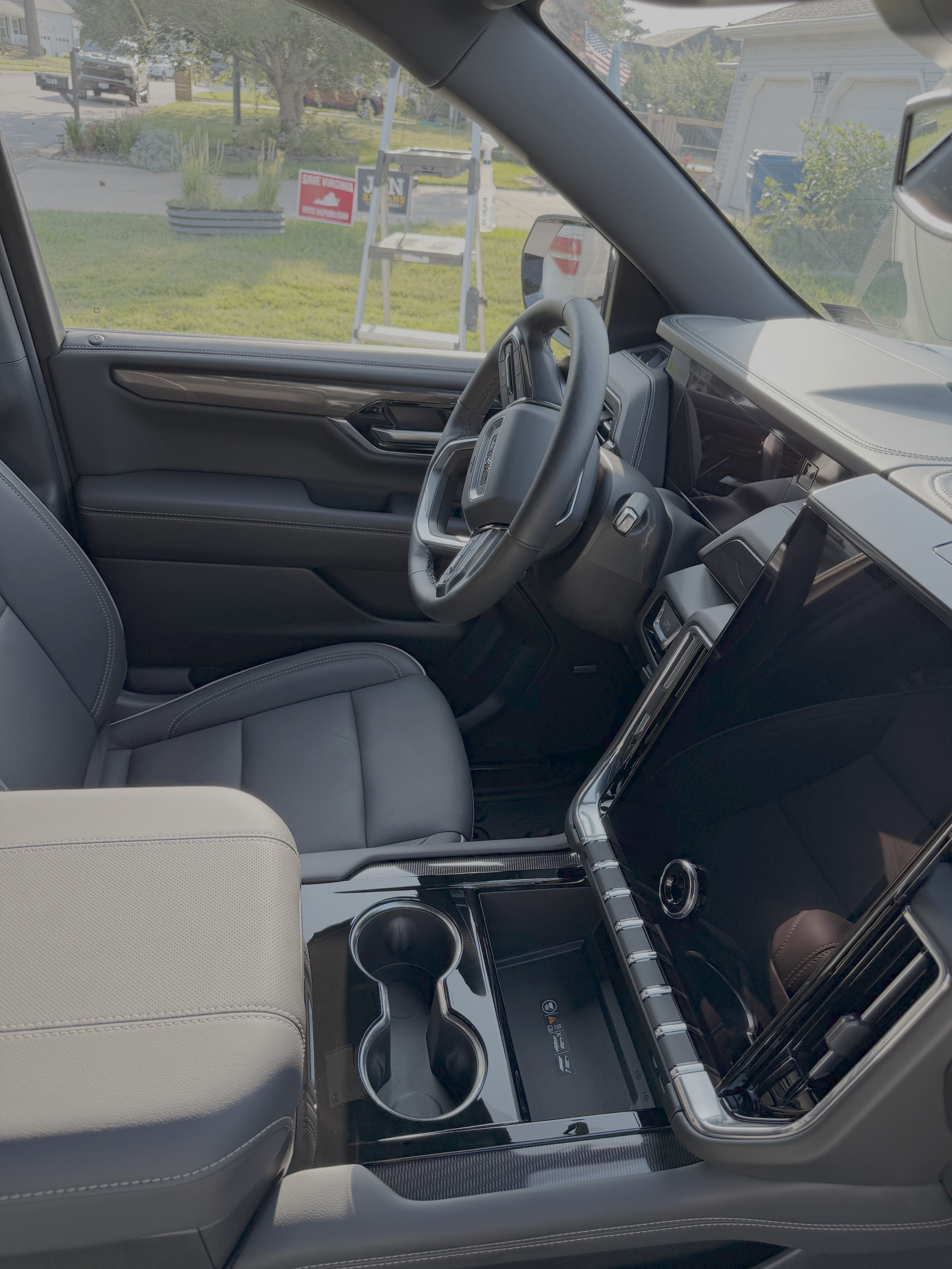 The interior of a modern vehicle with black and gray upholstery, a digital dashboard, cup holders, and a center console.