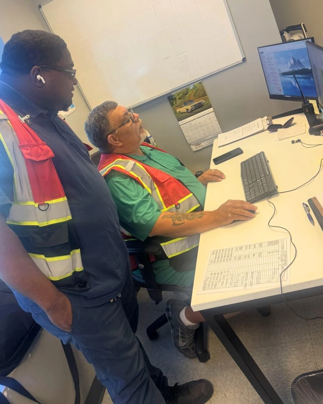 DNA Logistix team members in safety vests reviewing daily operations at a workstation, supporting nationwide third-party logistics warehousing and distribution services.