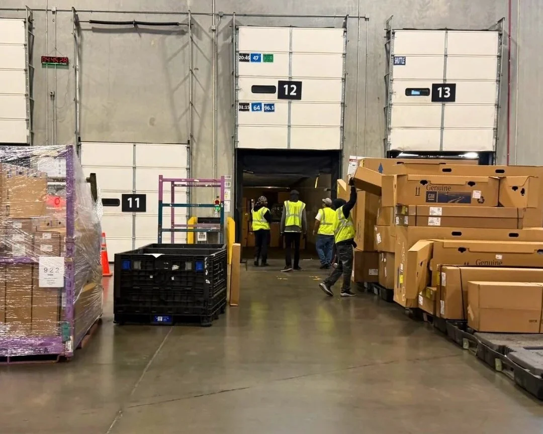 DNA Logistix warehouse loading dock with team members coordinating inbound freight and pallet inventory across multiple dock doors at a national 3PL distribution facility.