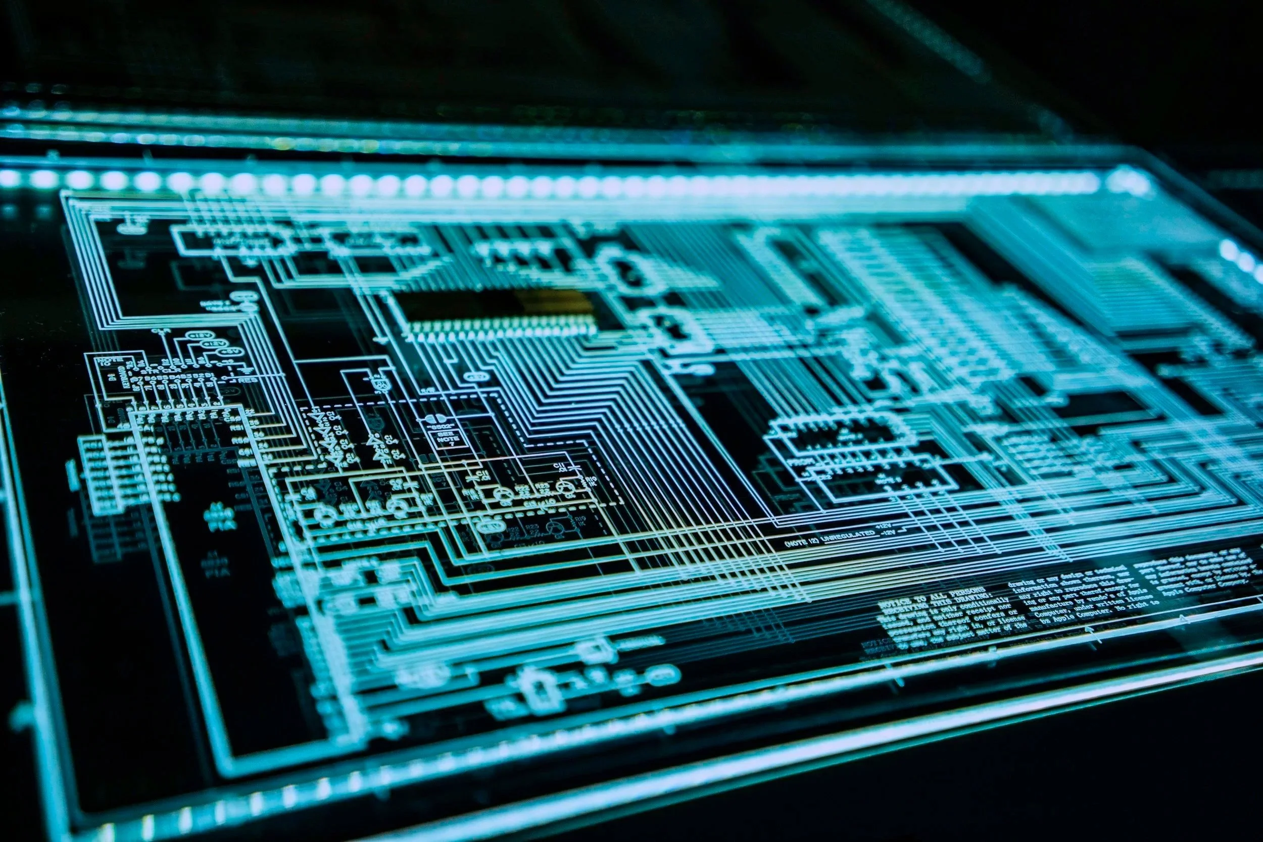 Close-up of a digital circuit board with blue glowing lines and electronic components, illustrating technology and electronics.