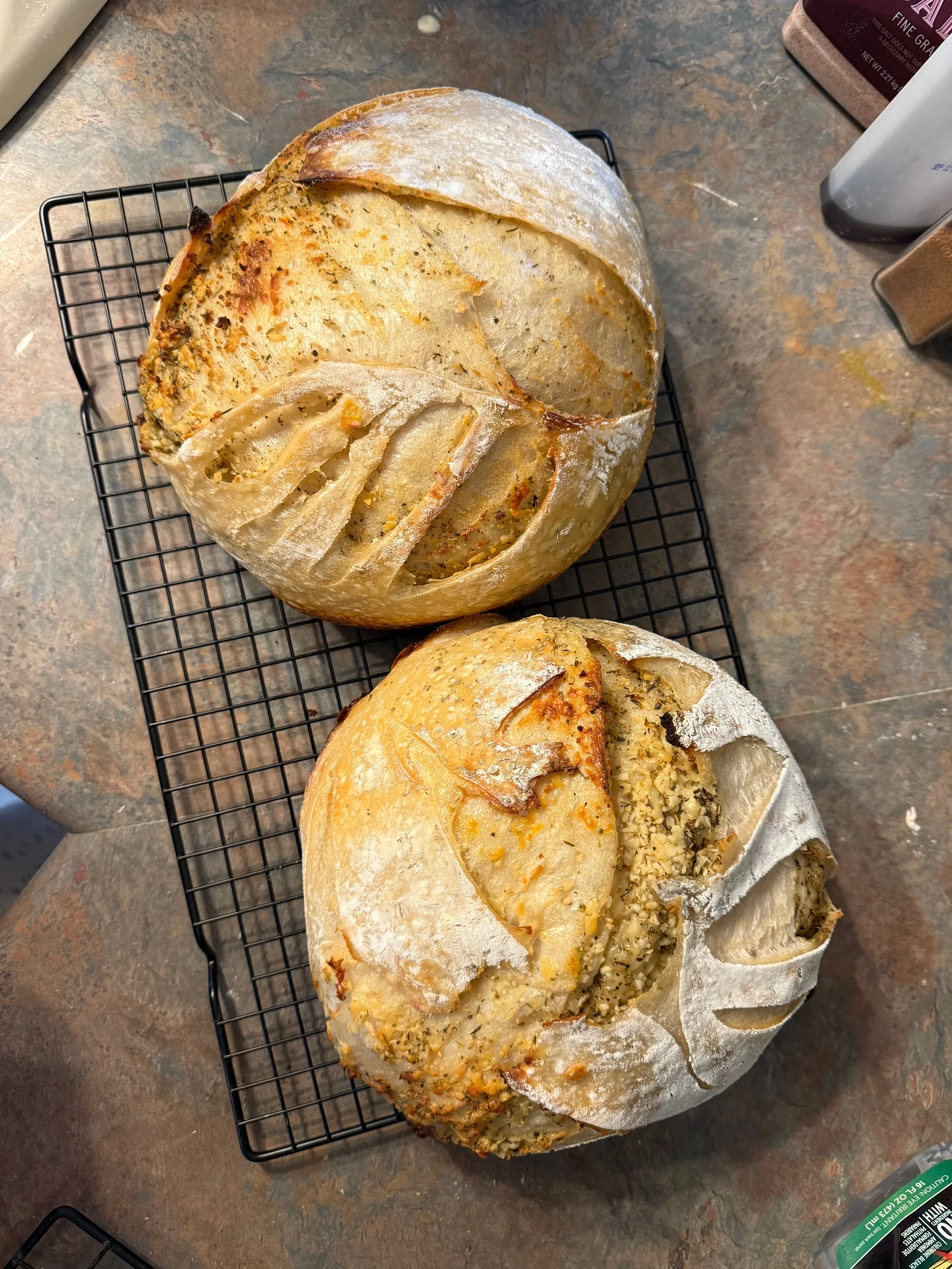 A loaf of bread with a sliced open top showing a creamy, crumbly filling with nuts and herbs.